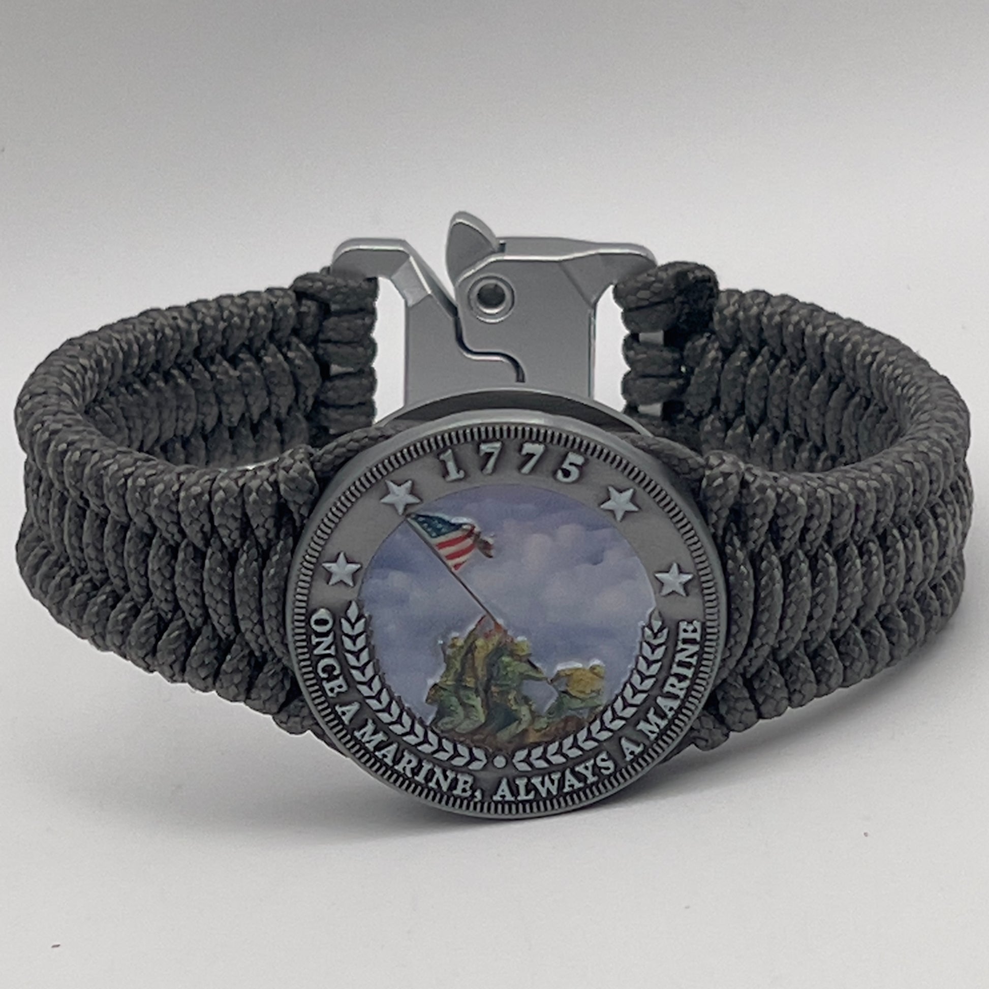 Thin, narrow, flexible and comfortable braided United States Marine Corps Iwo Jima bracelet featuring an antique silver plated UV painted Iwo Jima flag raising medallion, a silver Cobra style tactical buckle and woven with Charcoal Gray type-1 paracord.