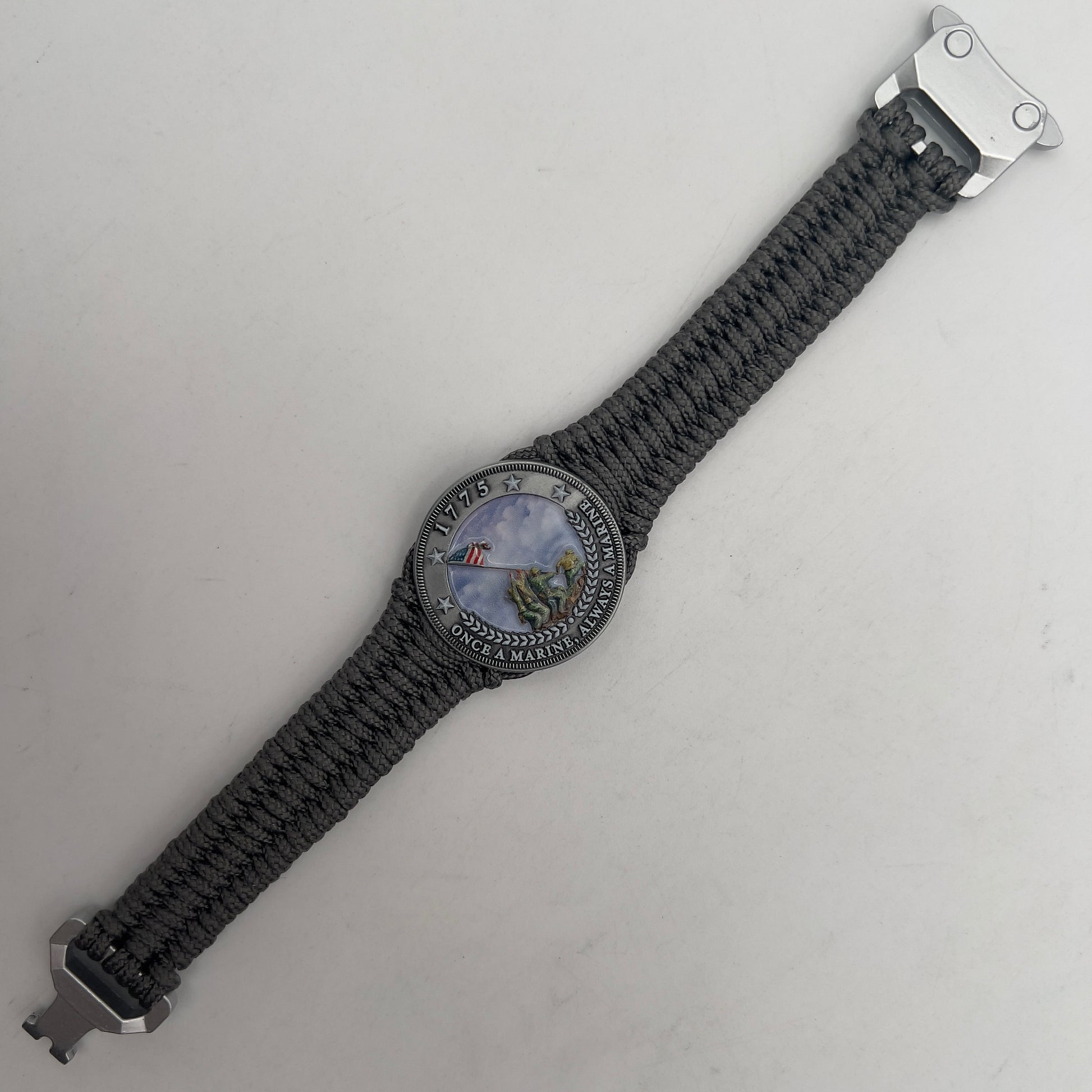 Thin, narrow, flexible and comfortable braided United States Marine Corps Iwo Jima bracelet featuring an antique silver plated UV painted Iwo Jima flag raising medallion, a silver Cobra style tactical buckle and woven with Charcoal Gray type-1 paracord.
