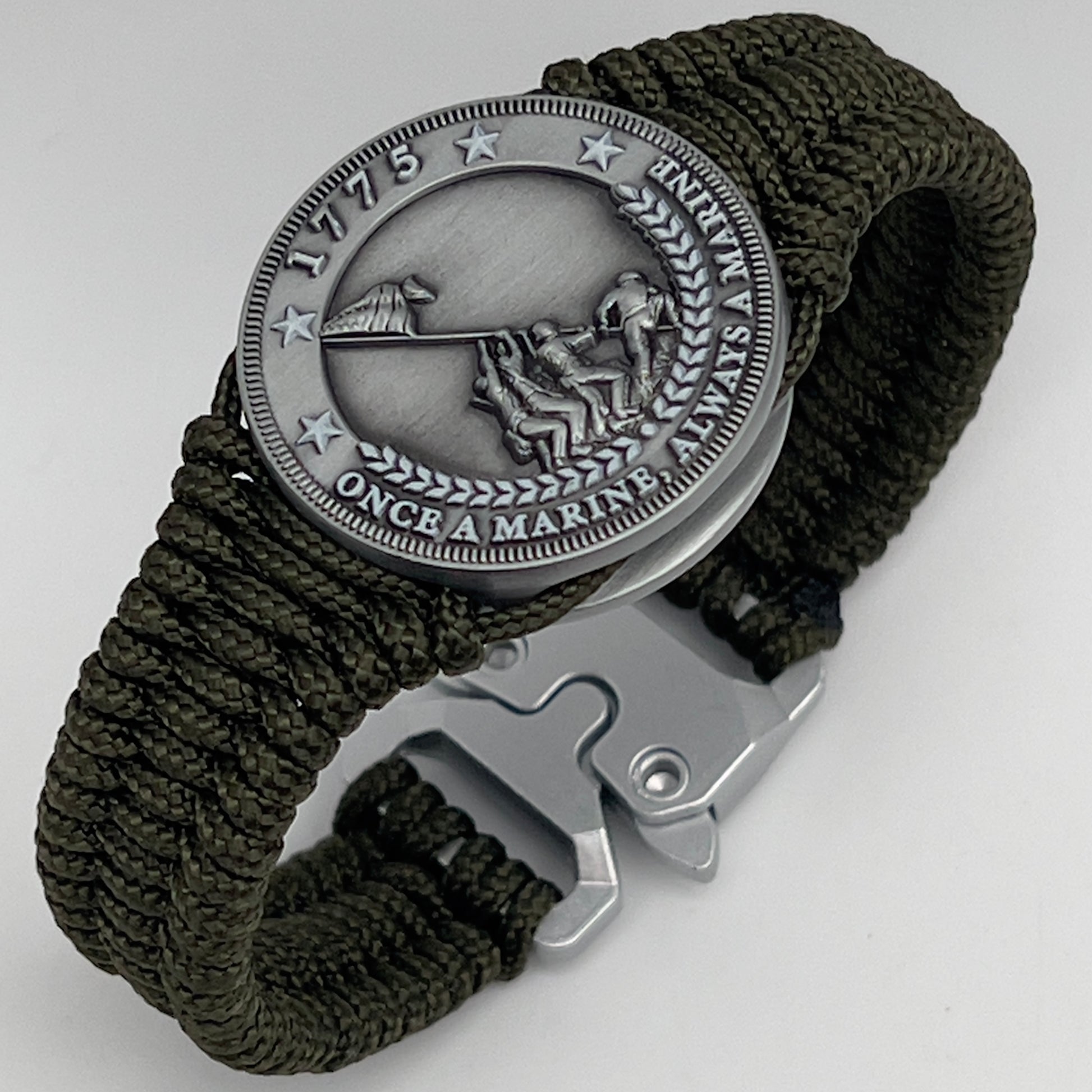 Thin, narrow, flexible and comfortable braided United States Marine Corps Iwo Jima bracelet featuring an antique silver plated UV painted Iwo Jima flag raising medallion, a silver Cobra style tactical buckle and woven with Olive Drab type-1 paracord.