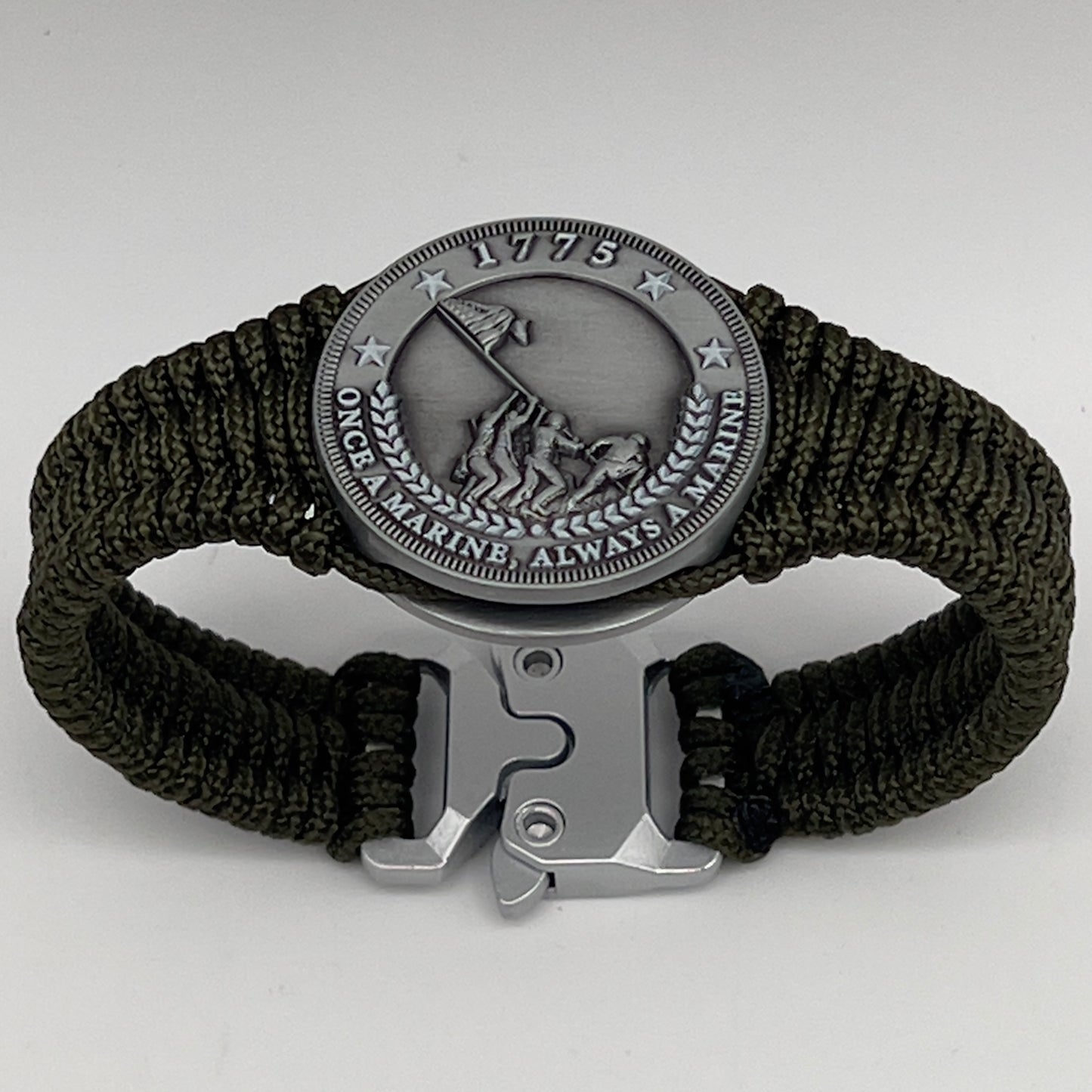 Thin, narrow, flexible and comfortable braided United States Marine Corps Iwo Jima bracelet featuring an antique silver plated UV painted Iwo Jima flag raising medallion, a silver Cobra style tactical buckle and woven with Olive Drab type-1 paracord.