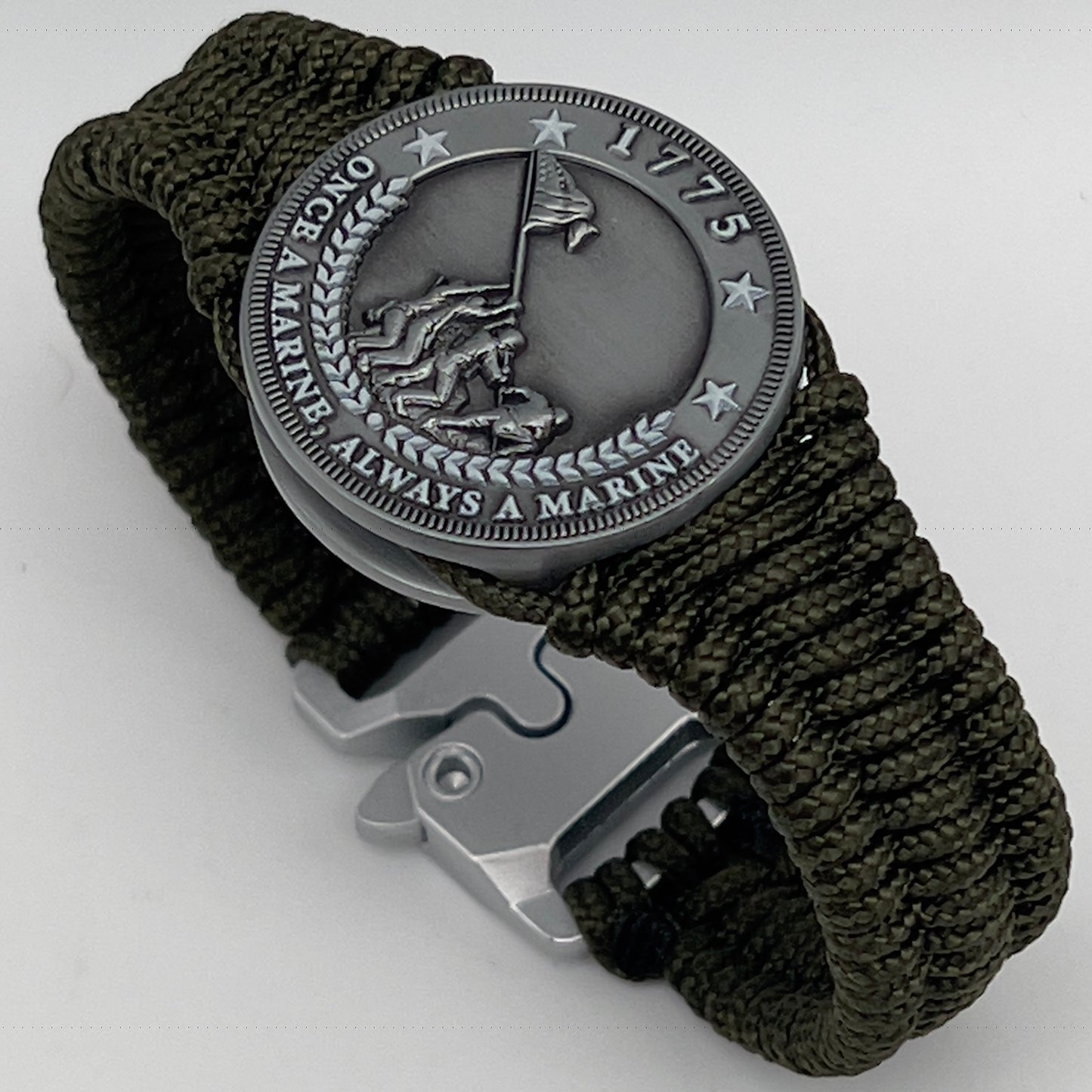 Thin, narrow, flexible and comfortable braided United States Marine Corps Iwo Jima bracelet featuring an antique silver plated UV painted Iwo Jima flag raising medallion, a silver Cobra style tactical buckle and woven with Olive Drab type-1 paracord.