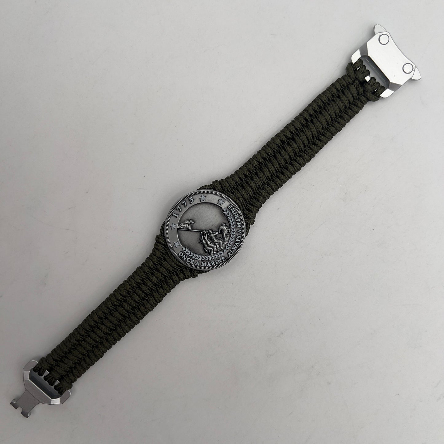 Thin, narrow, flexible and comfortable braided United States Marine Corps Iwo Jima bracelet featuring an antique silver plated UV painted Iwo Jima flag raising medallion, a silver Cobra style tactical buckle and woven with Olive Drab type-1 paracord.