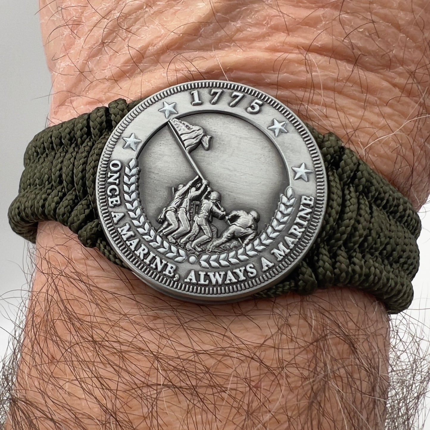 Thin, narrow, flexible and comfortable braided United States Marine Corps Iwo Jima bracelet featuring an antique silver plated UV painted Iwo Jima flag raising medallion, a silver Cobra style tactical buckle and woven with Olive Drab type-1 paracord.