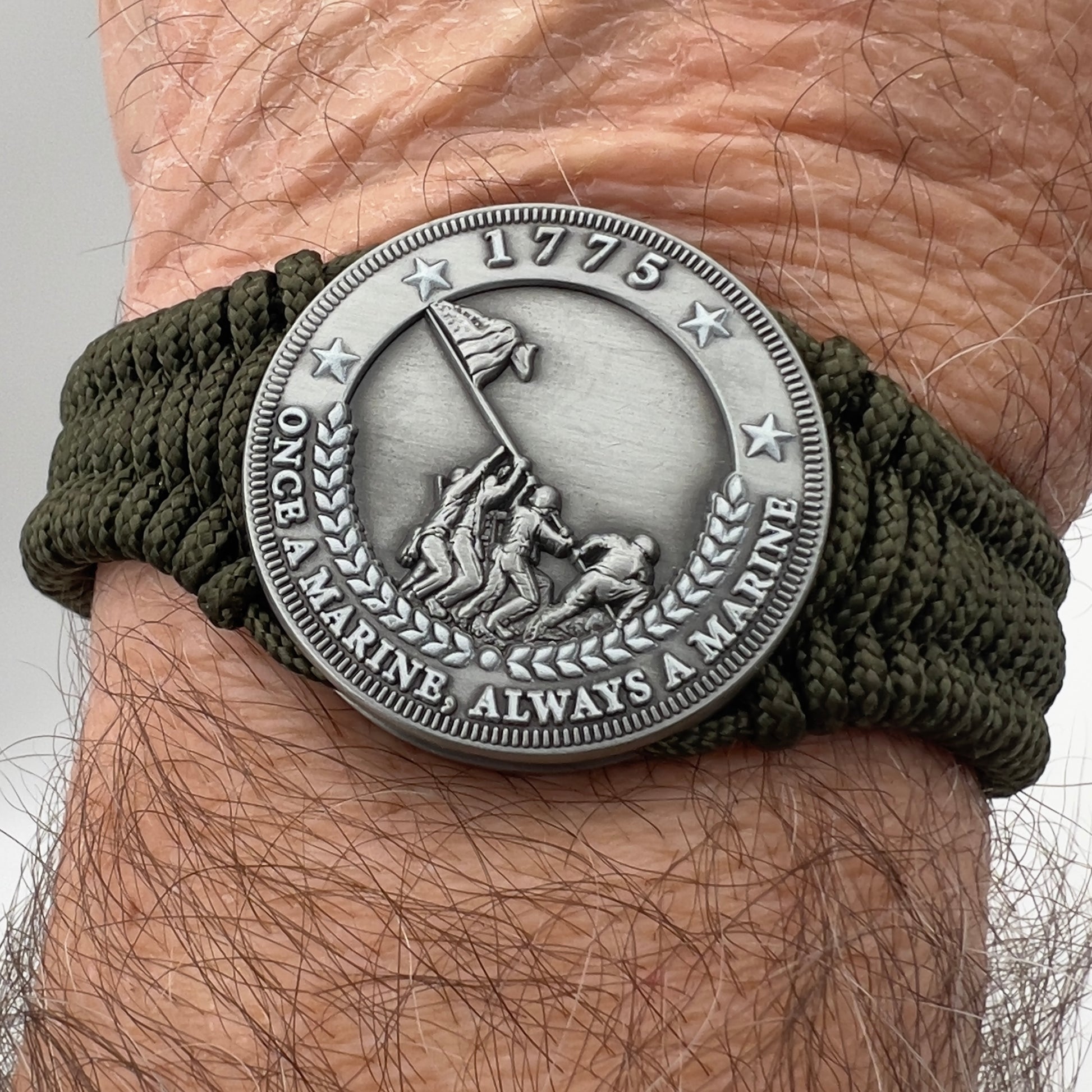 Thin, narrow, flexible and comfortable braided United States Marine Corps Iwo Jima bracelet featuring an antique silver plated UV painted Iwo Jima flag raising medallion, a silver Cobra style tactical buckle and woven with Olive Drab type-1 paracord.