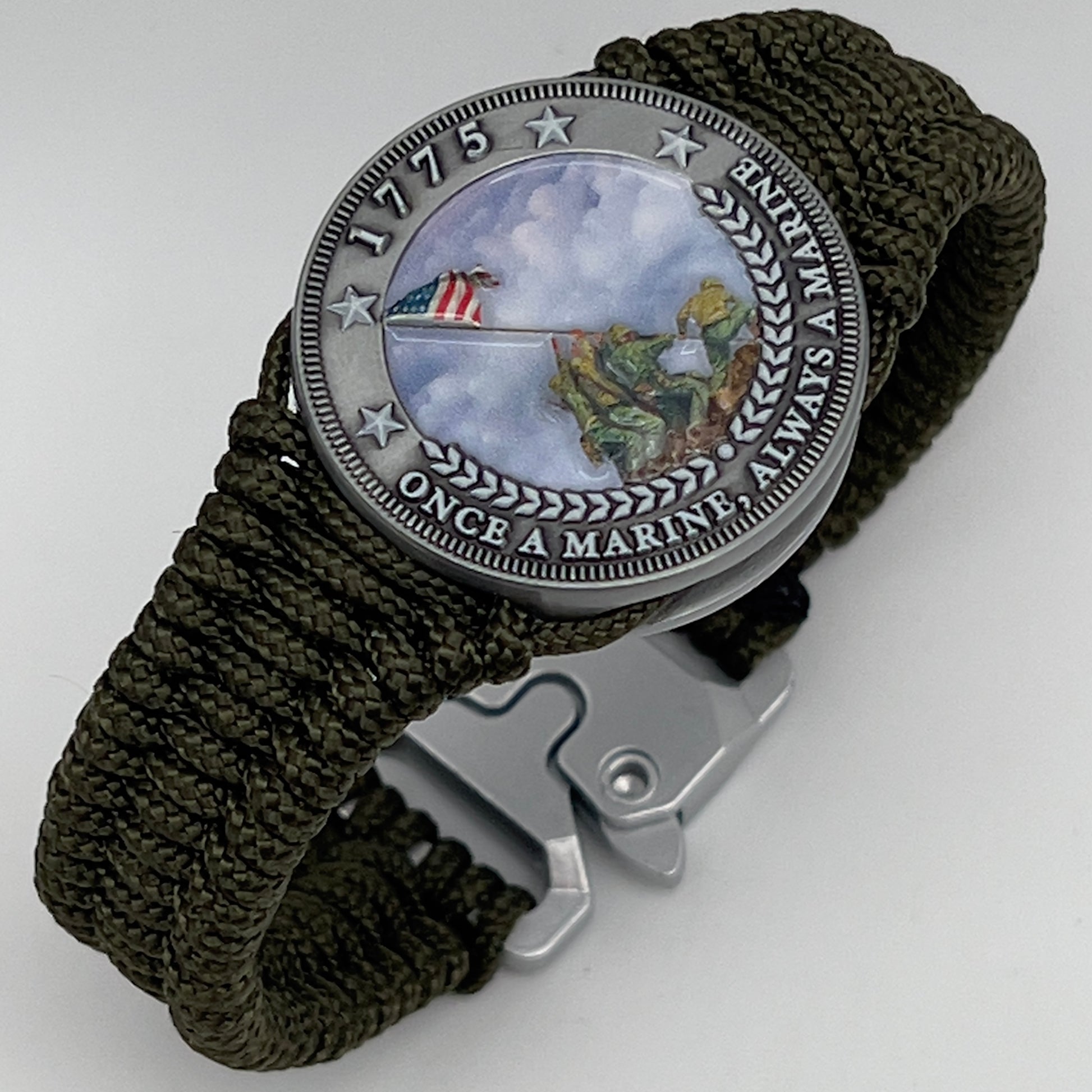 Thin, narrow, flexible and comfortable braided United States Marine Corps Iwo Jima bracelet featuring an antique silver plated UV painted Iwo Jima flag raising medallion, a silver Cobra style tactical buckle and woven with Olive Drab type-1 paracord.