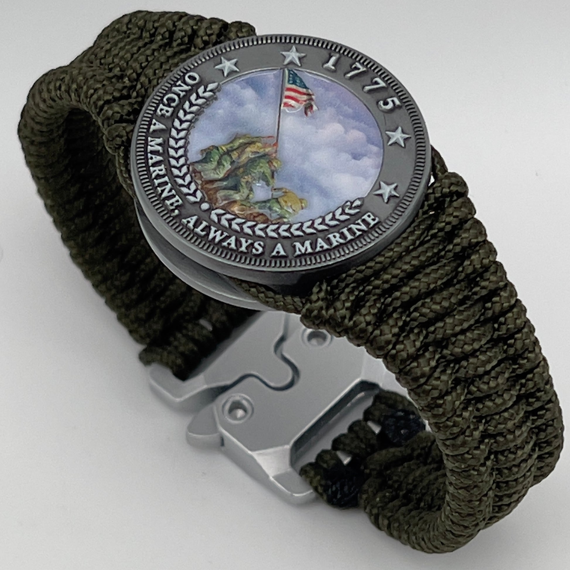 Thin, narrow, flexible and comfortable braided United States Marine Corps Iwo Jima bracelet featuring an antique silver plated UV painted Iwo Jima flag raising medallion, a silver Cobra style tactical buckle and woven with Olive Drab type-1 paracord.