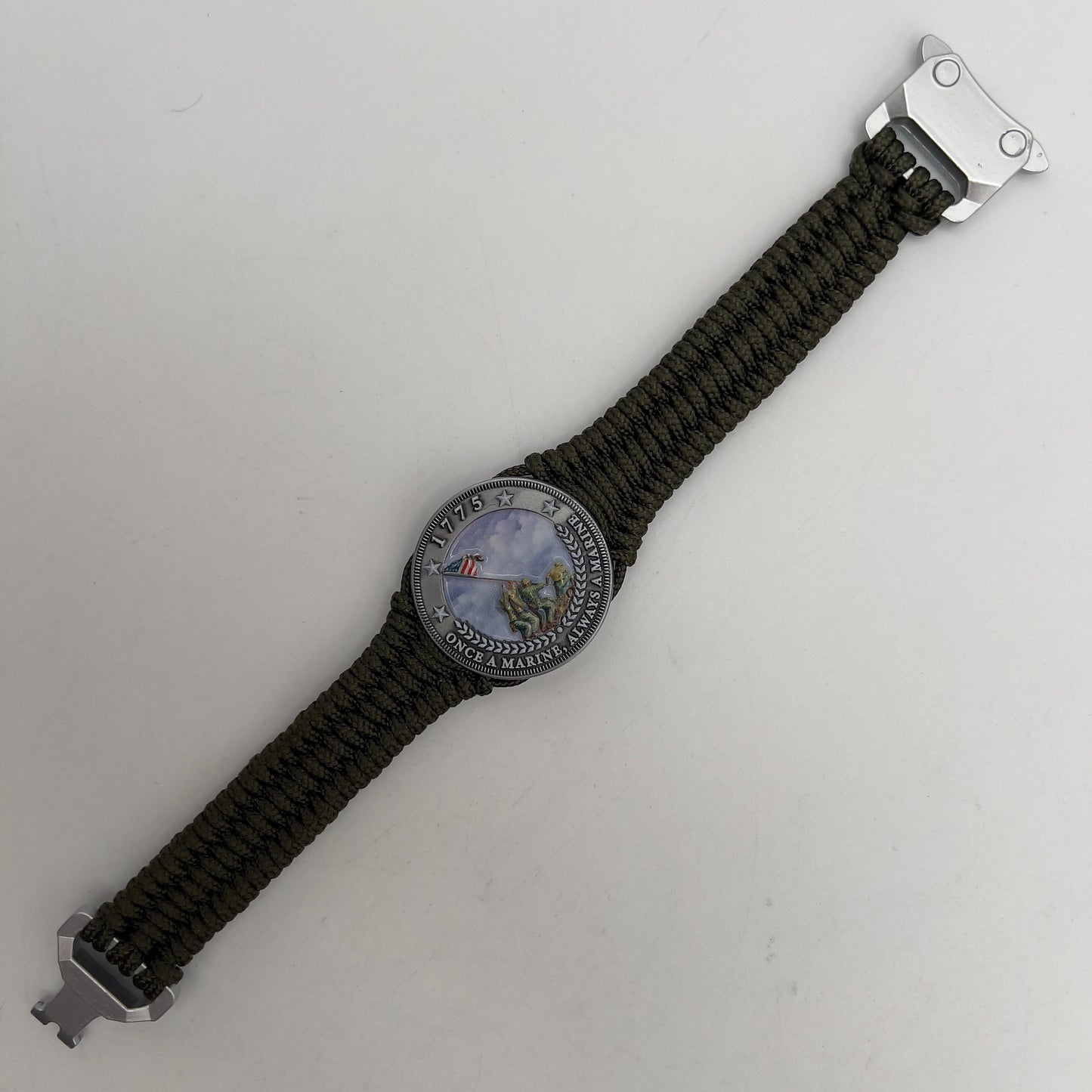 Thin, narrow, flexible and comfortable braided United States Marine Corps Iwo Jima bracelet featuring an antique silver plated UV painted Iwo Jima flag raising medallion, a silver Cobra style tactical buckle and woven with Olive Drab type-1 paracord.