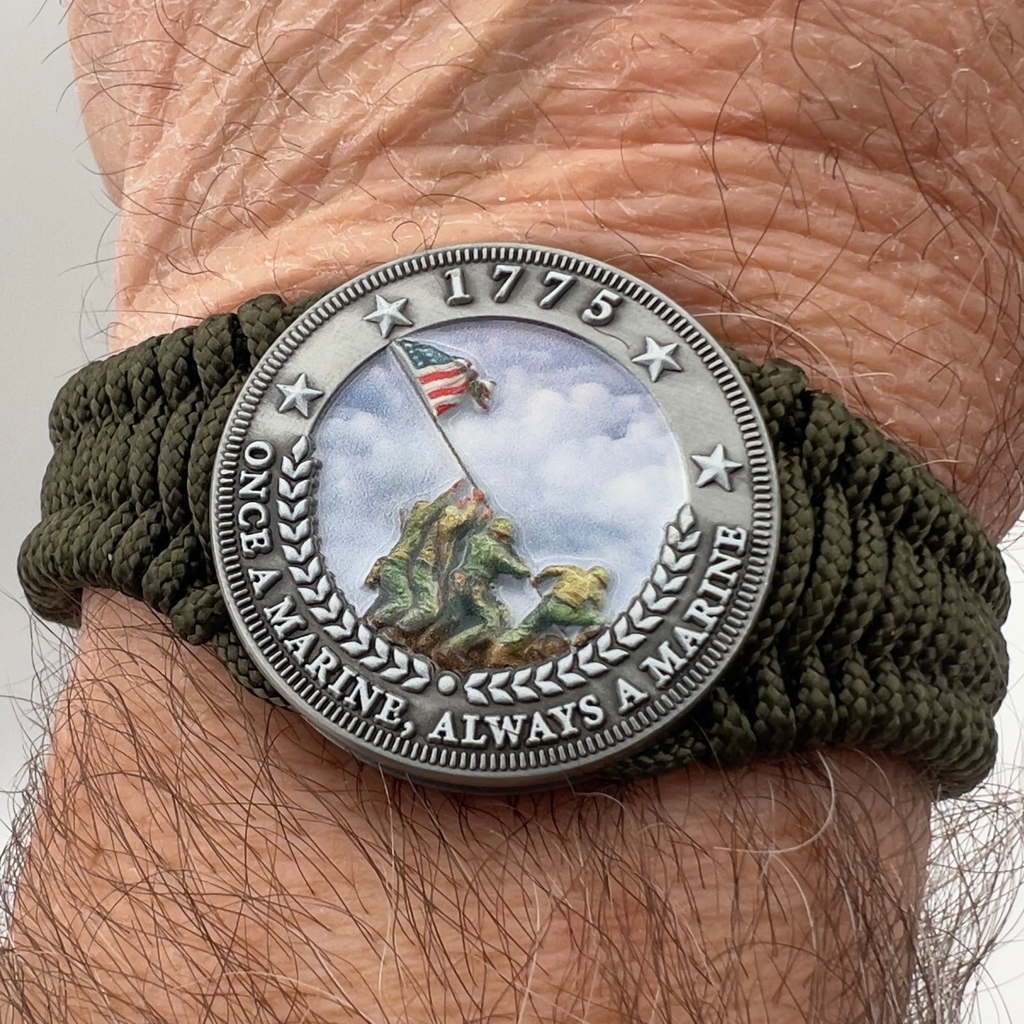 Thin, narrow, flexible and comfortable braided United States Marine Corps Iwo Jima bracelet featuring an antique silver plated UV painted Iwo Jima flag raising medallion, a silver Cobra style tactical buckle and woven with Olive Drab type-1 paracord.