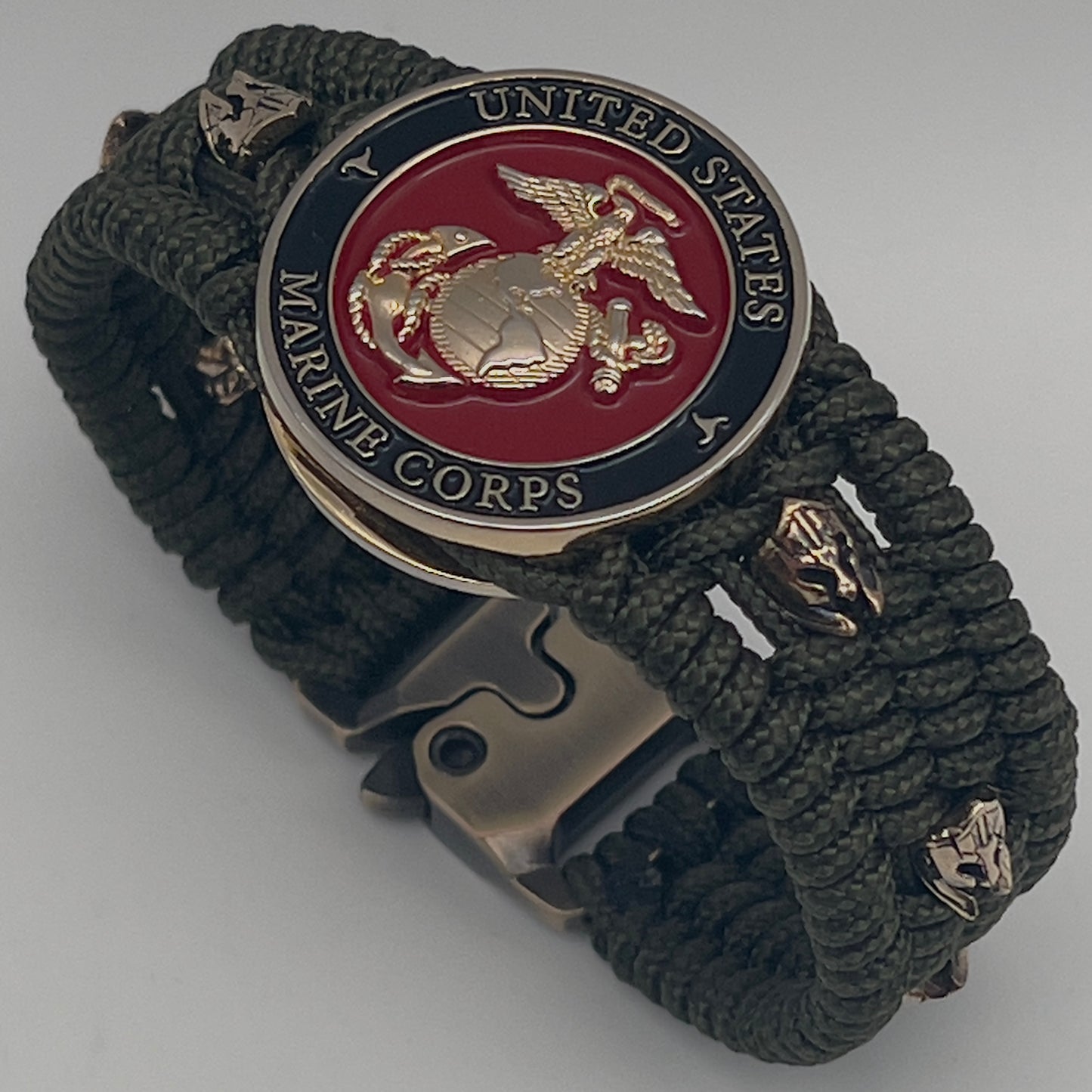 Thin, medium width, flexible and comfortable braided United States Marine Corps bracelet featuring a 24K gold plated USMC officer Eagle Globe and Anchor medallion, six Spartan micro beads, a gold Cobra style tactical buckle and woven with Olive Drab Type-1 paracord.