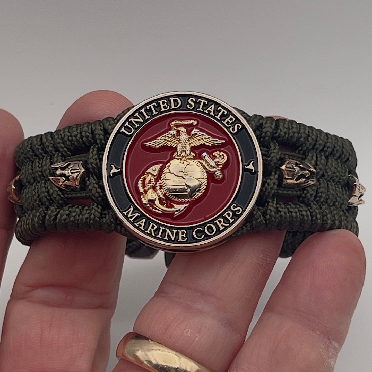 Thin, medium width, flexible and comfortable braided United States Marine Corps bracelet featuring a 24K gold plated USMC officer Eagle Globe and Anchor medallion, six Spartan micro beads, a gold Cobra style tactical buckle and woven with Olive Drab Type-1 paracord.