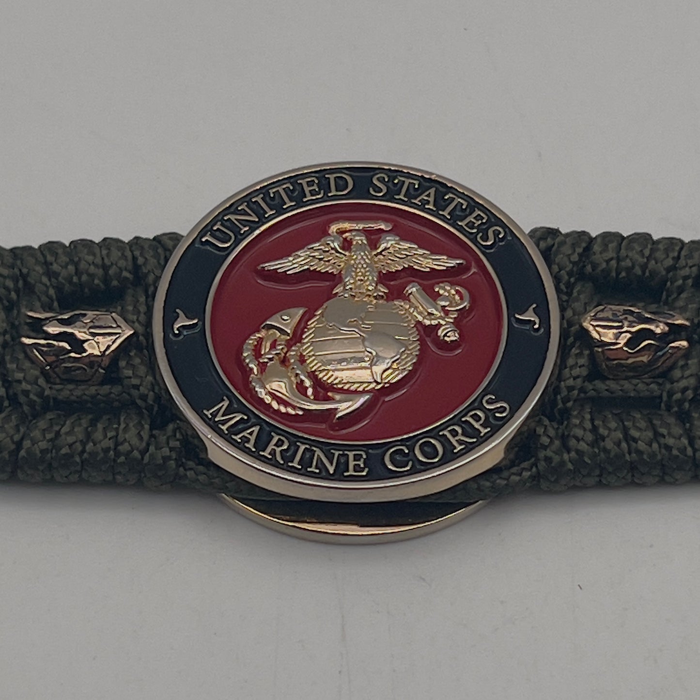 Thin, medium width, flexible and comfortable braided United States Marine Corps bracelet featuring a 24K gold plated USMC officer Eagle Globe and Anchor medallion, six Spartan micro beads, a gold Cobra style tactical buckle and woven with Olive Drab Type-1 paracord.