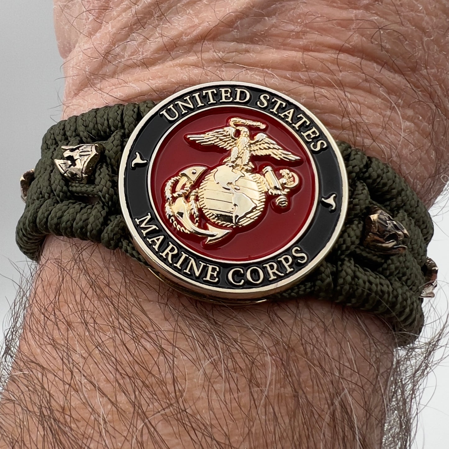 Thin, medium width, flexible and comfortable braided United States Marine Corps bracelet featuring a 24K gold plated USMC officer Eagle Globe and Anchor medallion, six Spartan micro beads, a gold Cobra style tactical buckle and woven with Olive Drab Type-1 paracord.