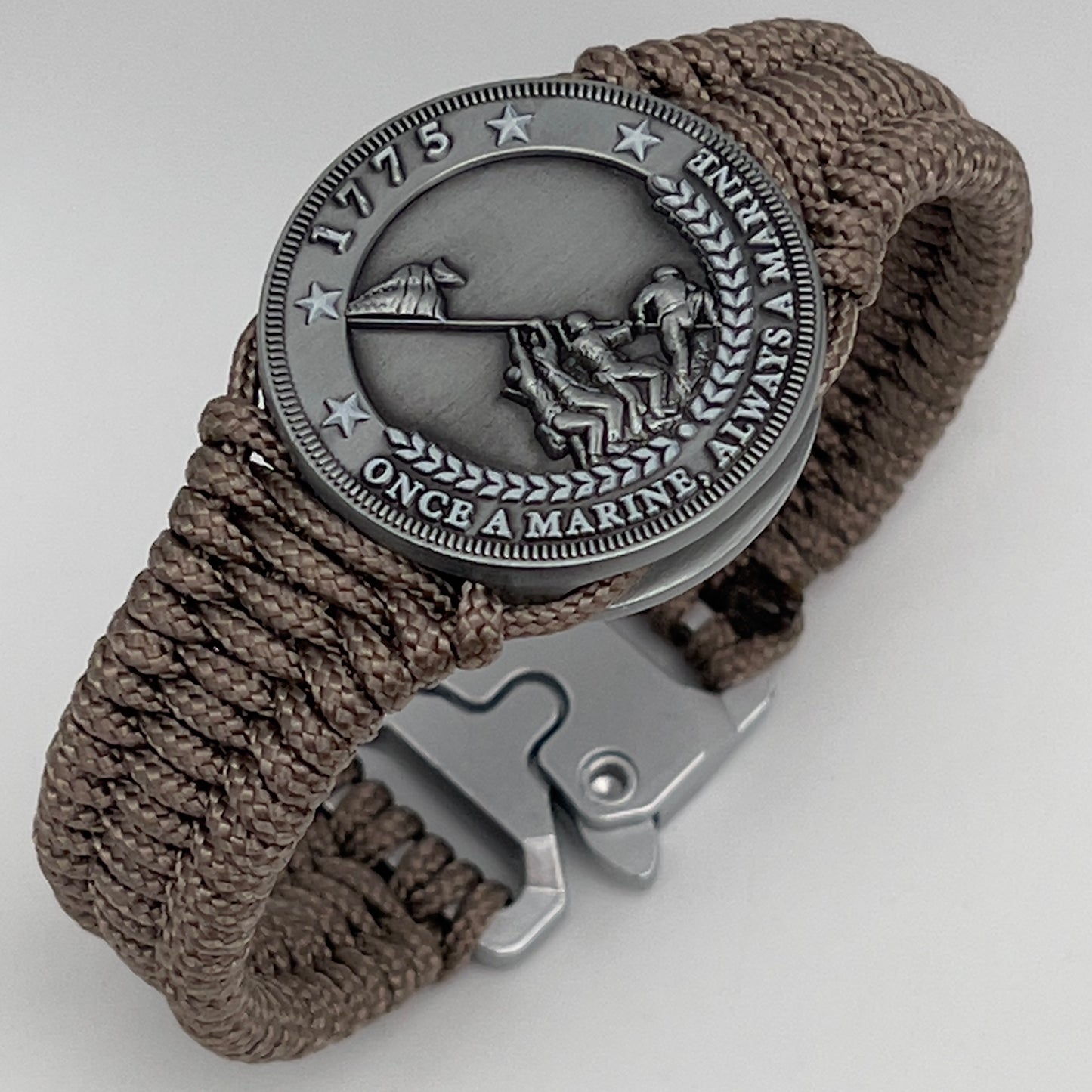 Thin, narrow, flexible and comfortable braided United States Marine Corps Iwo Jima bracelet featuring an antique silver plated Iwo Jima flag raising medallion, a silver Cobra style tactical buckle and woven with tan type-1 paracord.