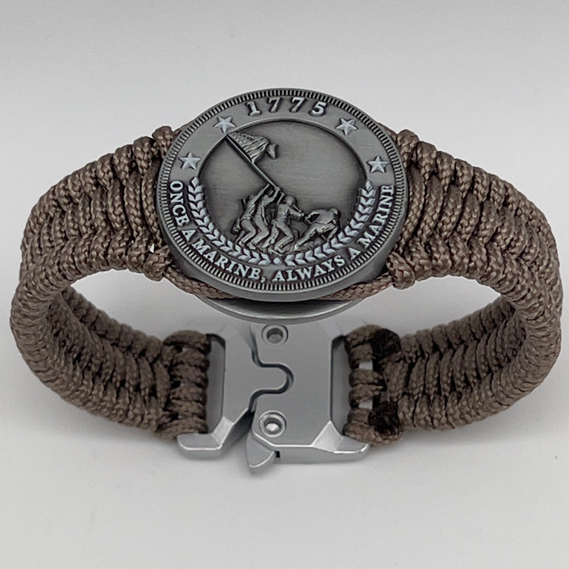 Thin, narrow, flexible and comfortable braided United States Marine Corps Iwo Jima bracelet featuring an antique silver plated Iwo Jima flag raising medallion, a silver Cobra style tactical buckle and woven with tan type-1 paracord.