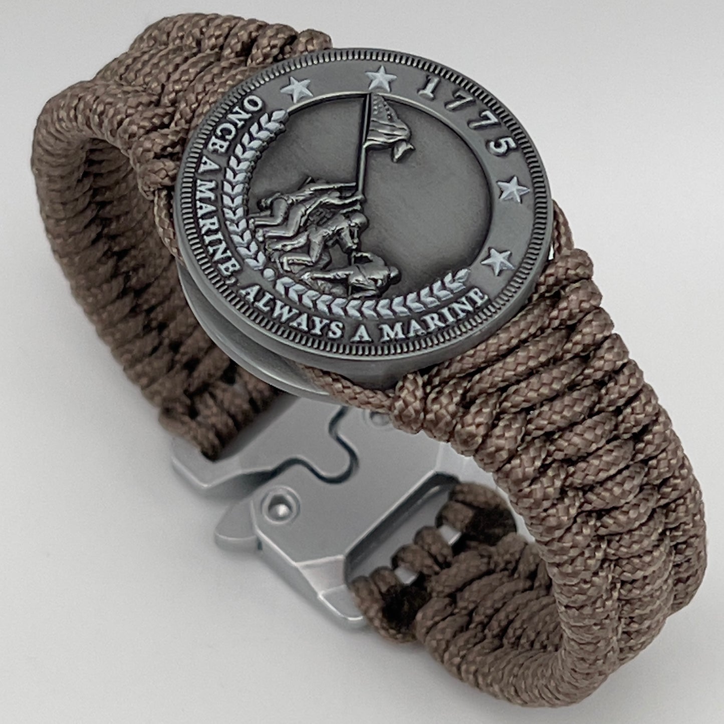 Thin, narrow, flexible and comfortable braided United States Marine Corps Iwo Jima bracelet featuring an antique silver plated Iwo Jima flag raising medallion, a silver Cobra style tactical buckle and woven with tan type-1 paracord.