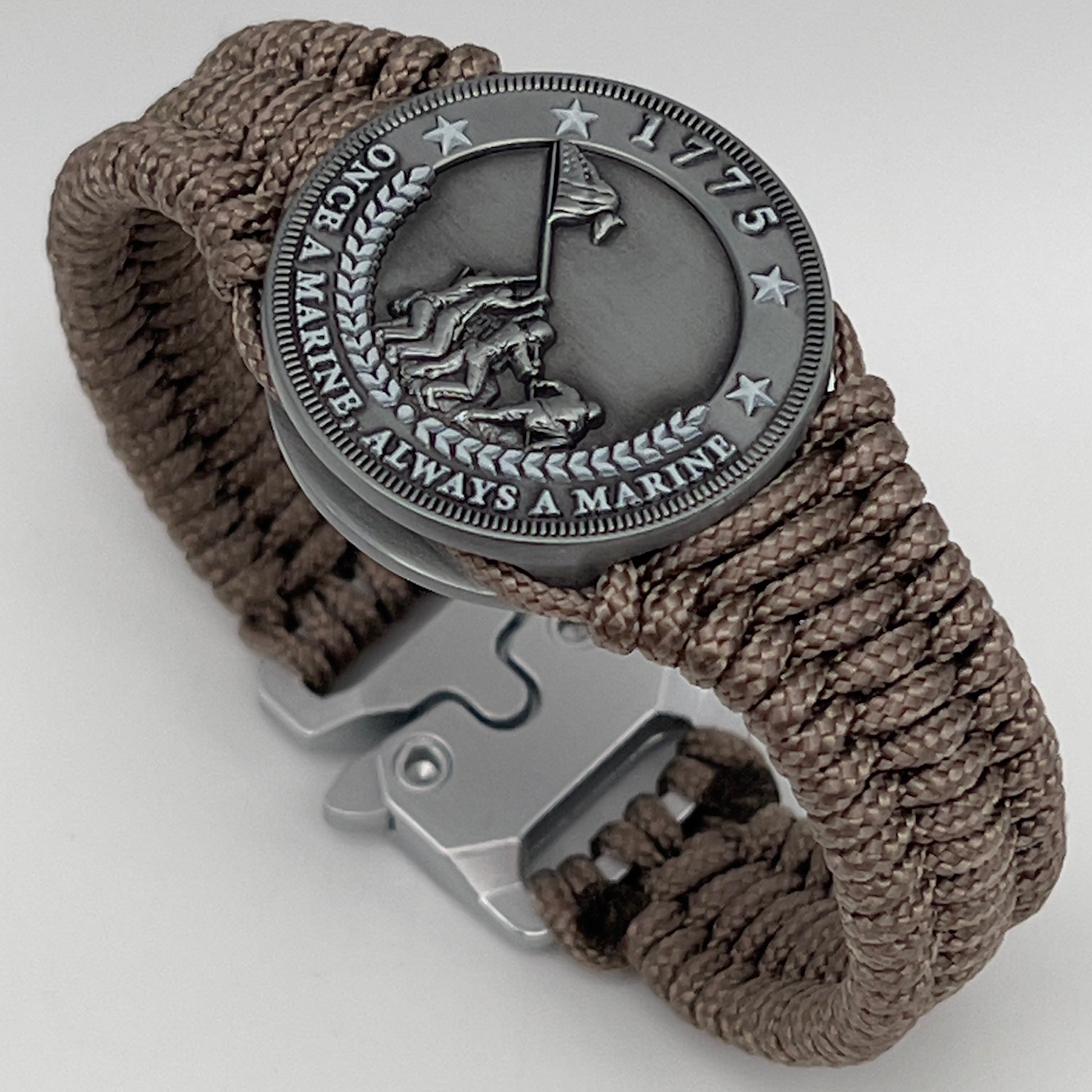 Thin, narrow, flexible and comfortable braided United States Marine Corps Iwo Jima bracelet featuring an antique silver plated Iwo Jima flag raising medallion, a silver Cobra style tactical buckle and woven with tan type-1 paracord.