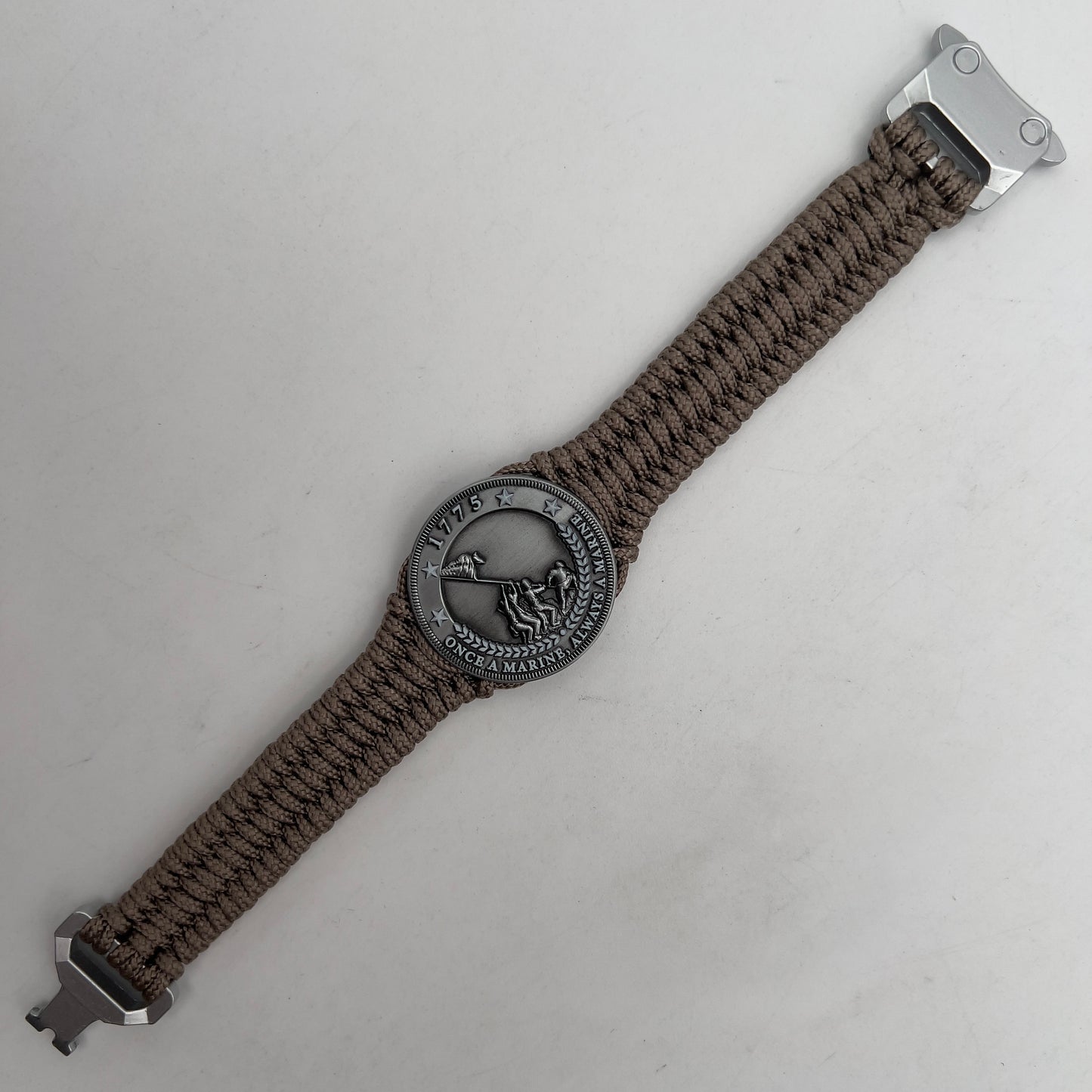 Thin, narrow, flexible and comfortable braided United States Marine Corps Iwo Jima bracelet featuring an antique silver plated Iwo Jima flag raising medallion, a silver Cobra style tactical buckle and woven with tan type-1 paracord.