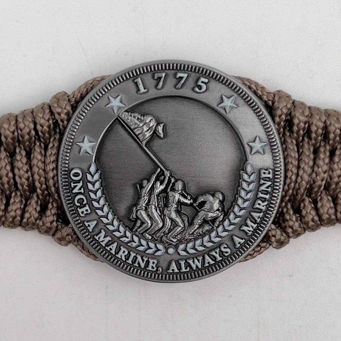 Thin, narrow, flexible and comfortable braided United States Marine Corps Iwo Jima bracelet featuring an antique silver plated Iwo Jima flag raising medallion, a silver Cobra style tactical buckle and woven with tan type-1 paracord.