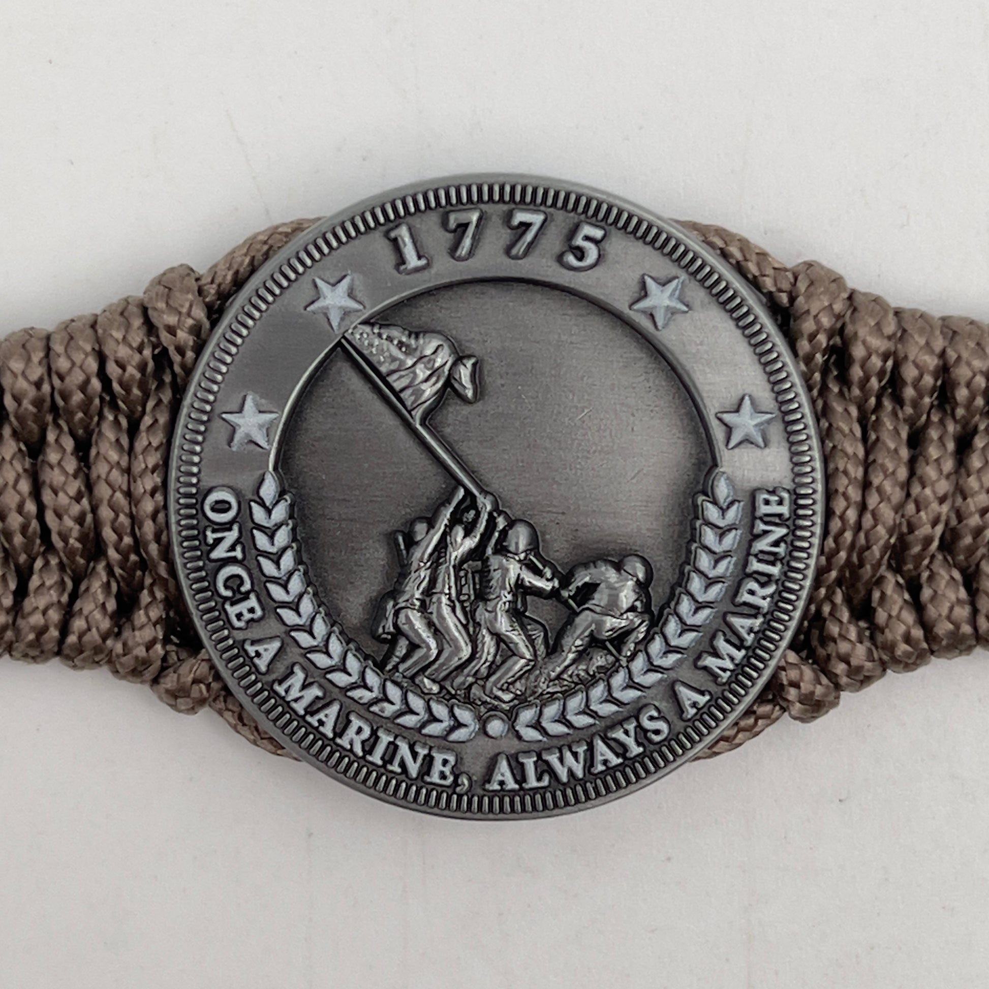 Thin, narrow, flexible and comfortable braided United States Marine Corps Iwo Jima bracelet featuring an antique silver plated Iwo Jima flag raising medallion, a silver Cobra style tactical buckle and woven with tan type-1 paracord.