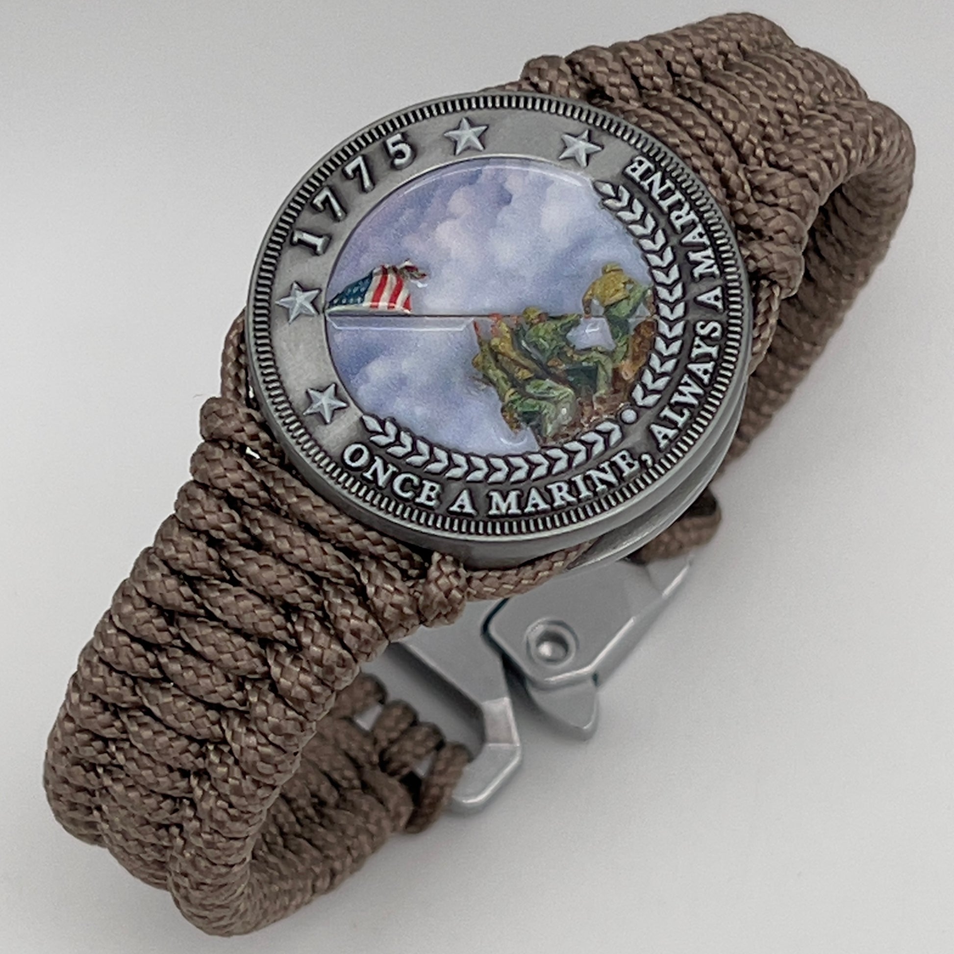 Thin, narrow, flexible and comfortable braided United States Marine Corps Iwo Jima bracelet featuring an antique silver plated UV painted Iwo Jima flag raising medallion, a silver Cobra style tactical buckle and woven with tan type-1 paracord.