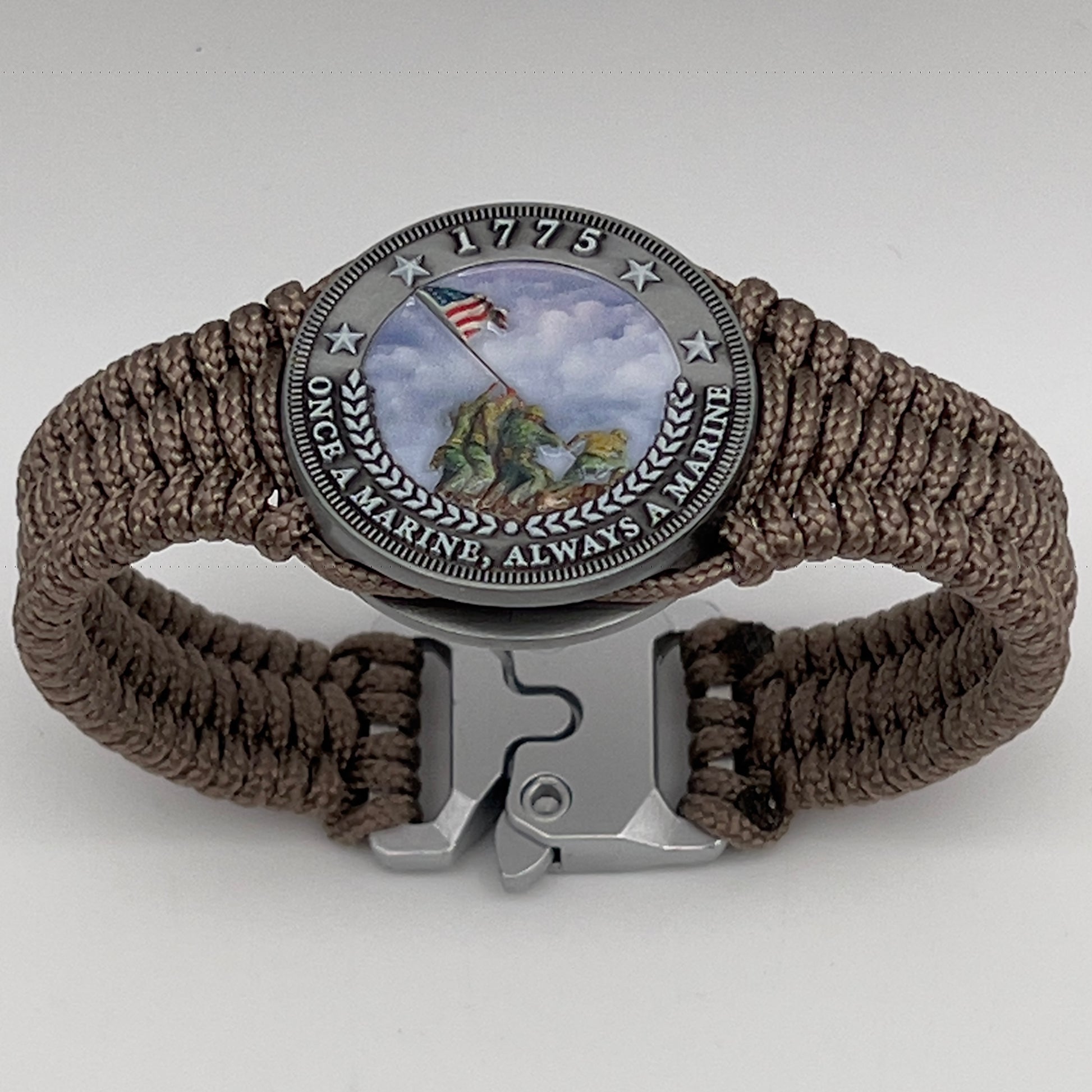 Thin, narrow, flexible and comfortable braided United States Marine Corps Iwo Jima bracelet featuring an antique silver plated UV painted Iwo Jima flag raising medallion, a silver Cobra style tactical buckle and woven with tan type-1 paracord.