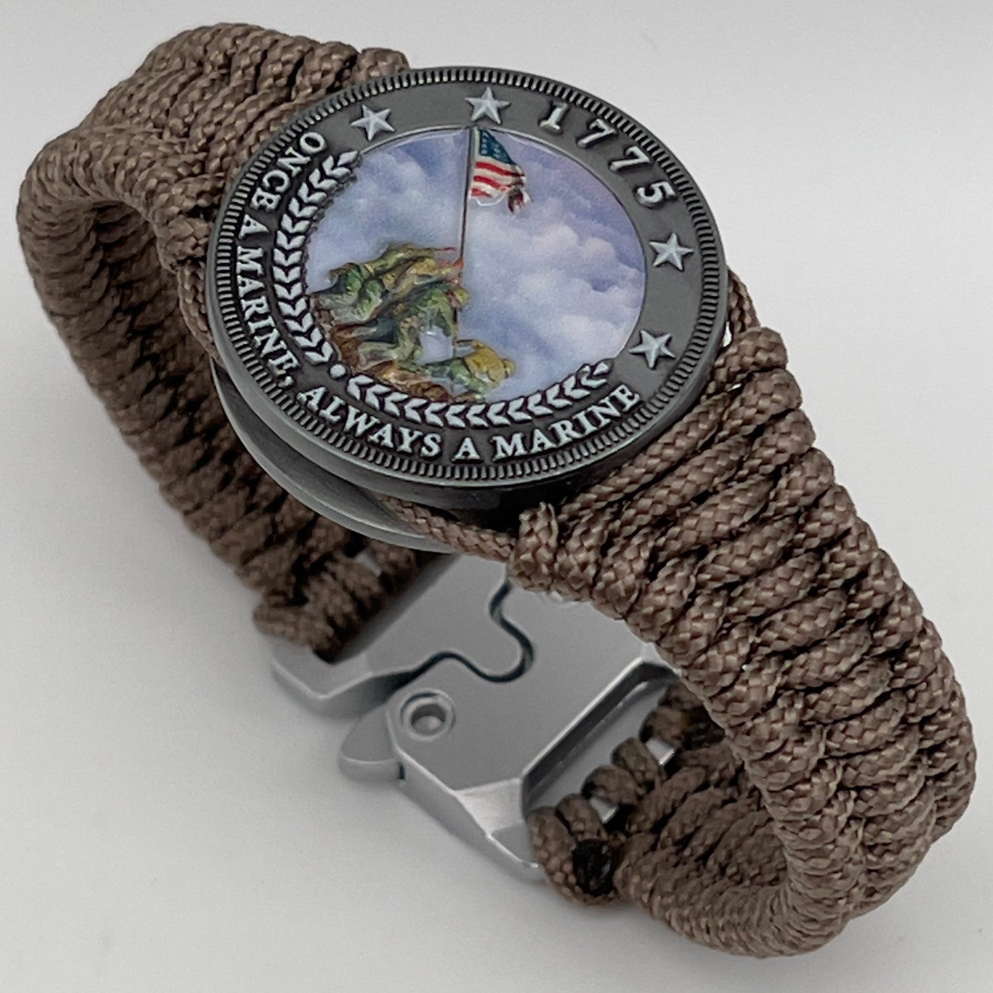Thin, narrow, flexible and comfortable braided United States Marine Corps Iwo Jima bracelet featuring an antique silver plated UV painted Iwo Jima flag raising medallion, a silver Cobra style tactical buckle and woven with tan type-1 paracord.