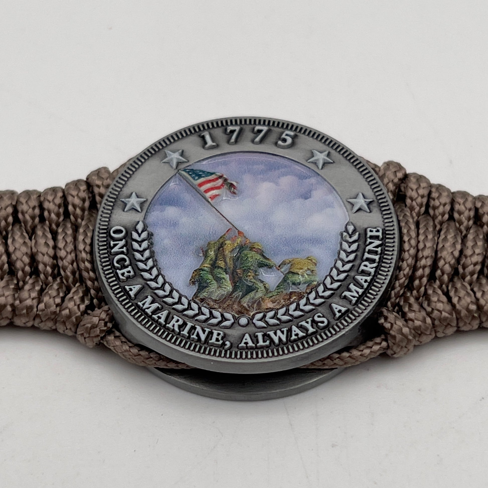 Thin, narrow, flexible and comfortable braided United States Marine Corps Iwo Jima bracelet featuring an antique silver plated UV painted Iwo Jima flag raising medallion, a silver Cobra style tactical buckle and woven with tan type-1 paracord.