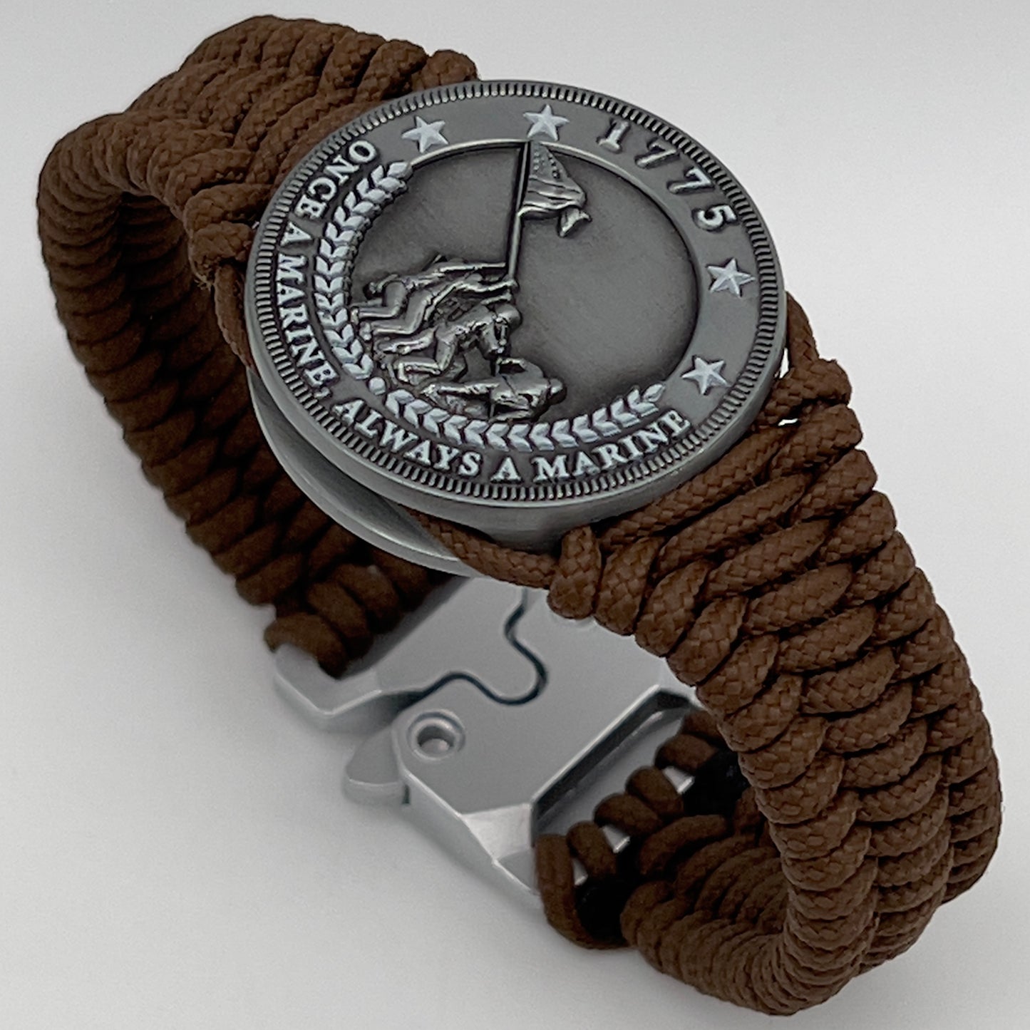 Thin, narrow, flexible and comfortable braided United States Marine Corps Iwo Jima bracelet featuring an antique silver plated Iwo Jima flag raising medallion, a silver Cobra style tactical buckle and woven with Coyote Brown type-1 paracord.