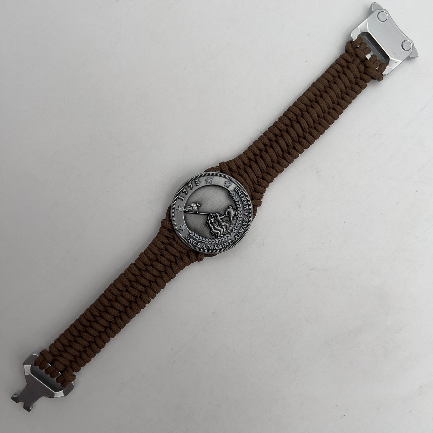 Thin, narrow, flexible and comfortable braided United States Marine Corps Iwo Jima bracelet featuring an antique silver plated Iwo Jima flag raising medallion, a silver Cobra style tactical buckle and woven with Coyote Brown type-1 paracord.