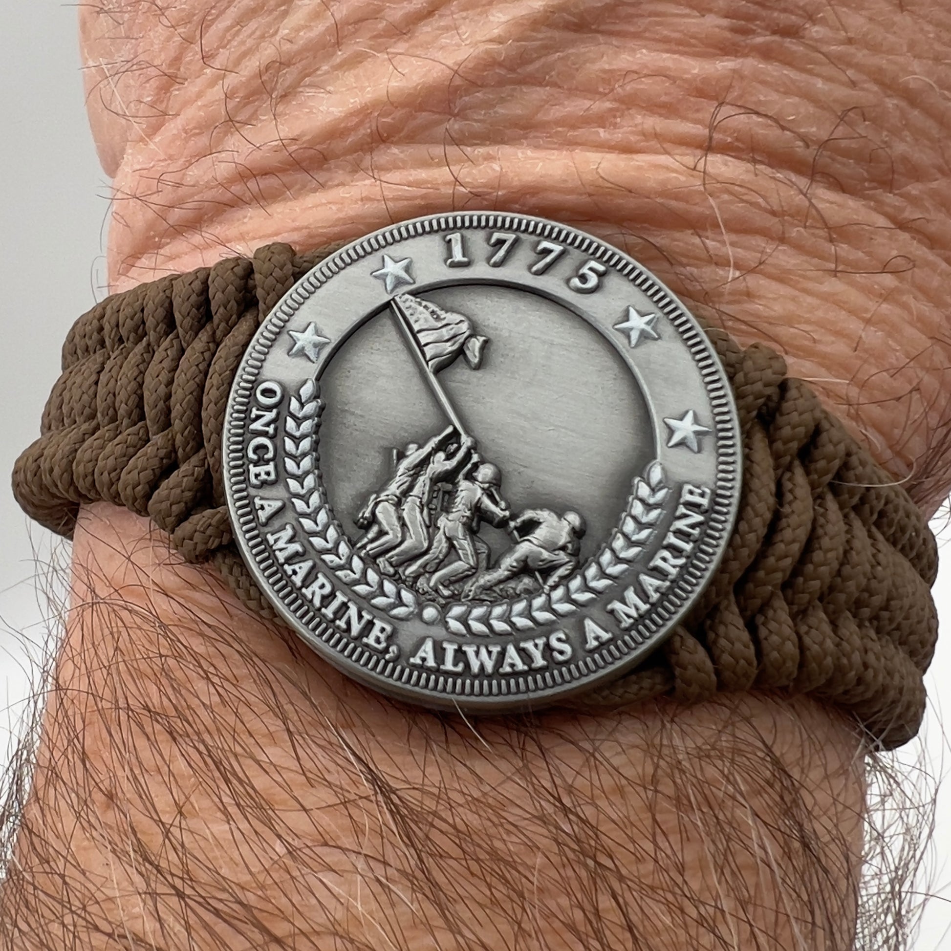 Thin, narrow, flexible and comfortable braided United States Marine Corps Iwo Jima bracelet featuring an antique silver plated Iwo Jima flag raising medallion, a silver Cobra style tactical buckle and woven with Coyote Brown type-1 paracord.