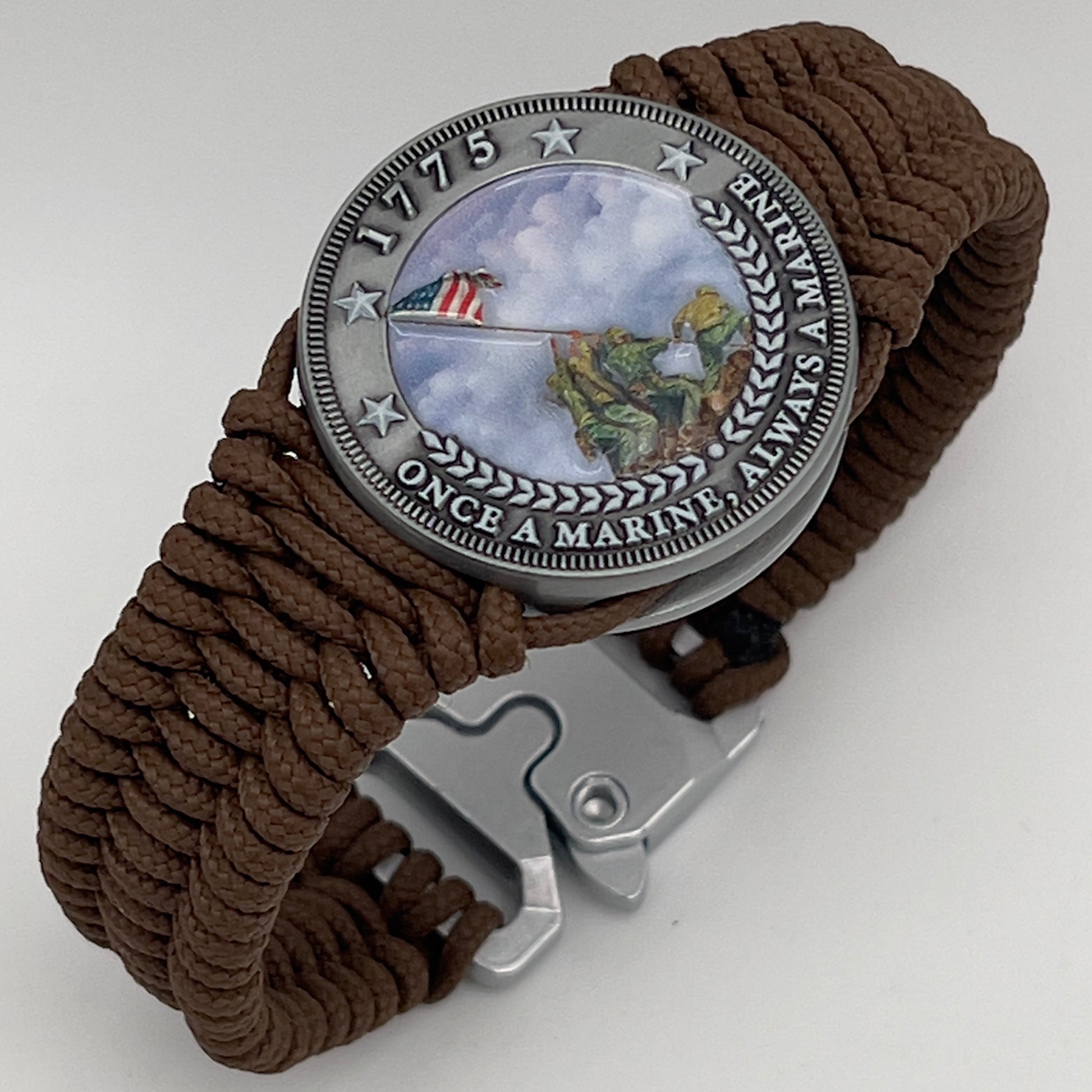 Thin, narrow, flexible and comfortable braided United States Marine Corps Iwo Jima bracelet featuring an antique silver plated UV painted Iwo Jima flag raising medallion, a silver Cobra style tactical buckle and woven with Coyote Brown type-1 paracord.
