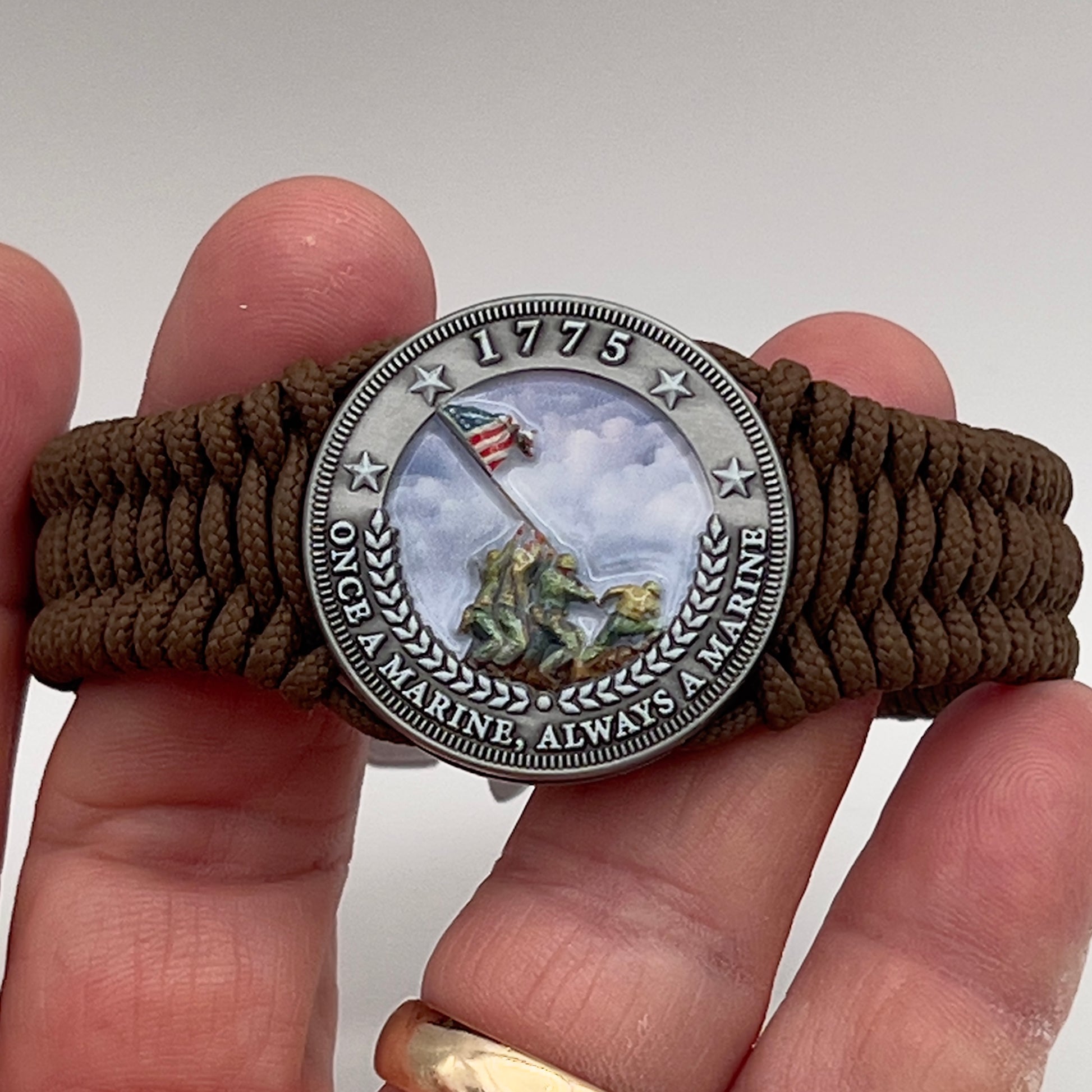 Thin, narrow, flexible and comfortable braided United States Marine Corps Iwo Jima bracelet featuring an antique silver plated UV painted Iwo Jima flag raising medallion, a silver Cobra style tactical buckle and woven with Coyote Brown type-1 paracord.
