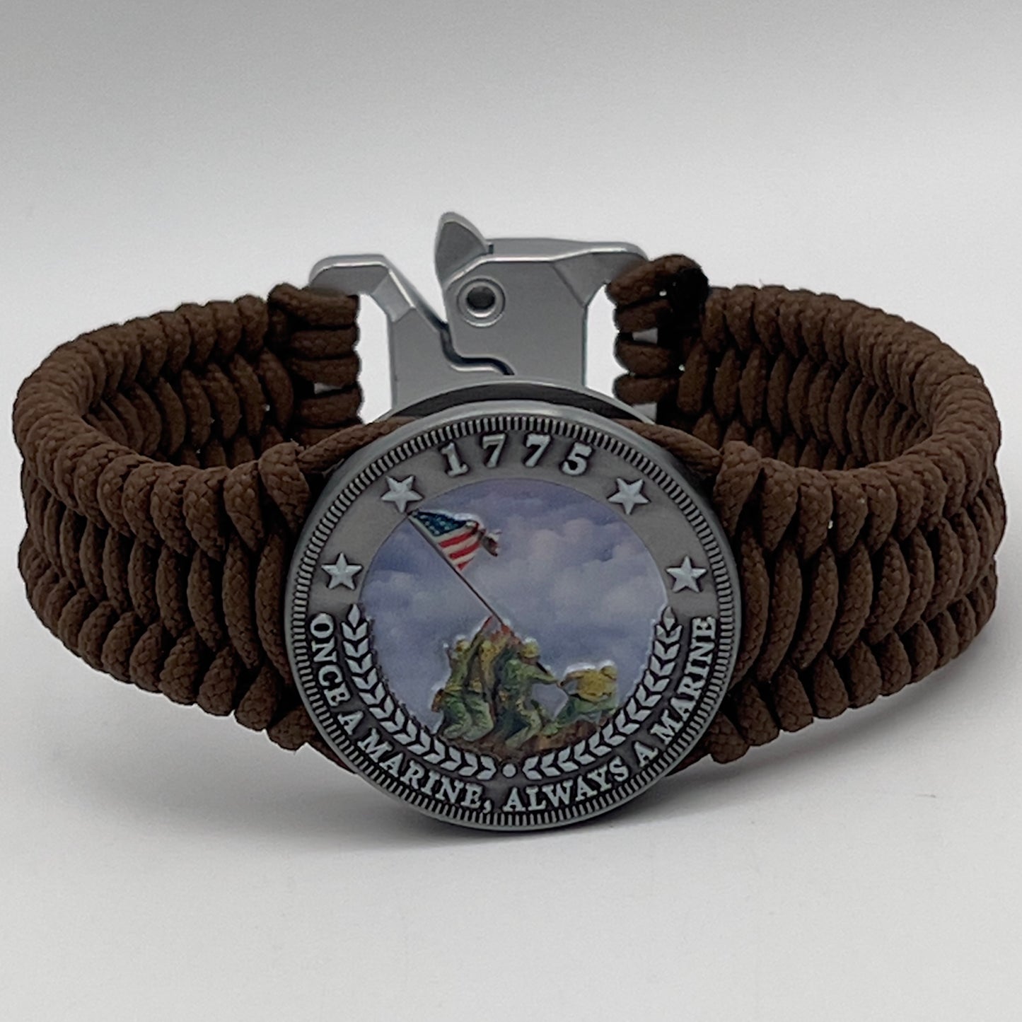 Thin, narrow, flexible and comfortable braided United States Marine Corps Iwo Jima bracelet featuring an antique silver plated UV painted Iwo Jima flag raising medallion, a silver Cobra style tactical buckle and woven with Coyote Brown type-1 paracord.