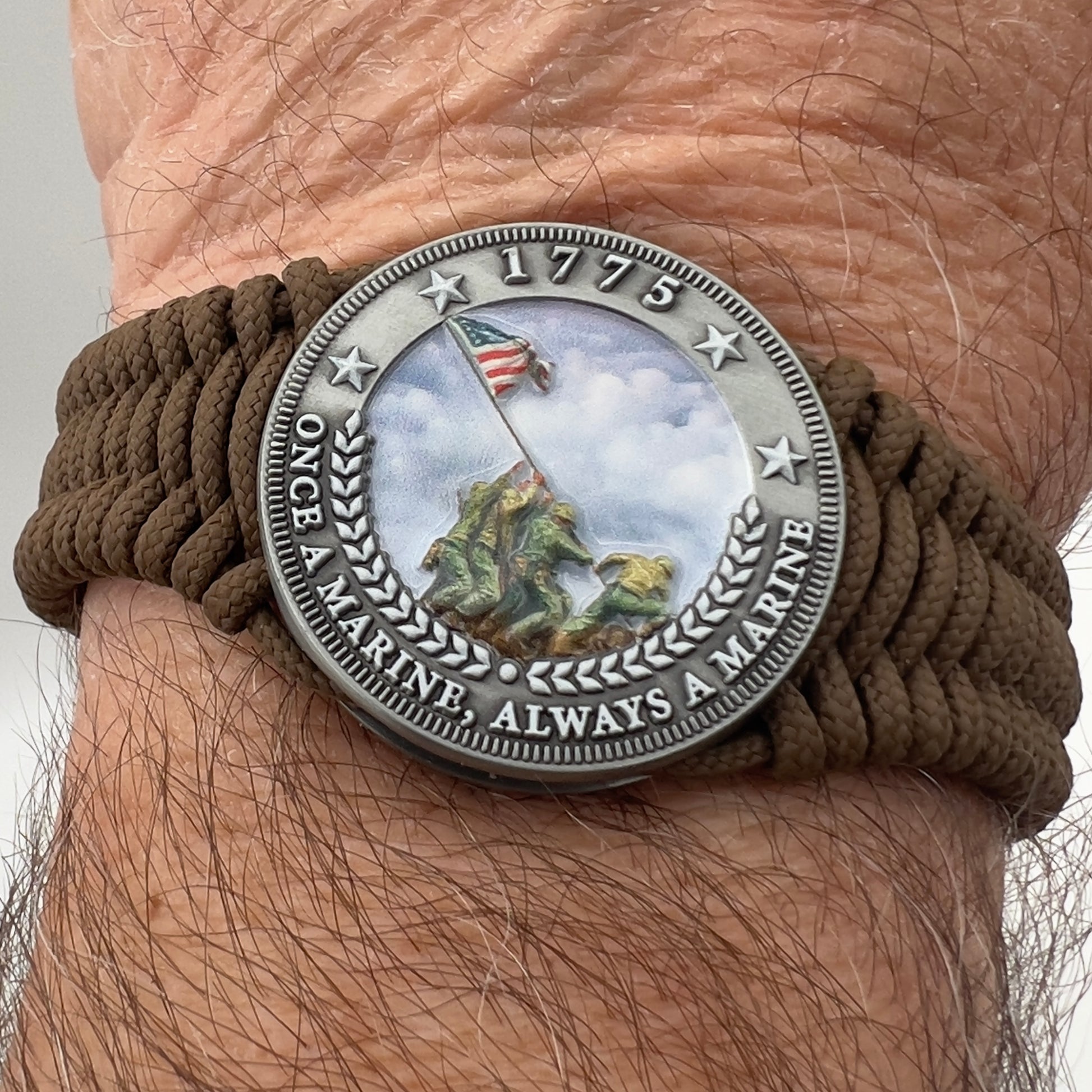 Thin, narrow, flexible and comfortable braided United States Marine Corps Iwo Jima bracelet featuring an antique silver plated UV painted Iwo Jima flag raising medallion, a silver Cobra style tactical buckle and woven with Coyote Brown type-1 paracord.