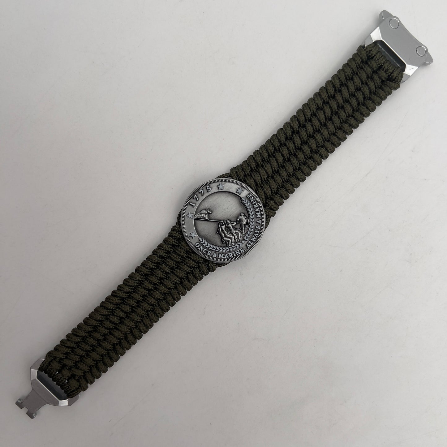 Thin, wide, flexible and comfortable braided United States Marine Corps Iwo Jima bracelet featuring an antique silver plated Iwo Jima flag raising medallion, a silver Cobra style tactical buckle and woven with olive drab type-1 paracord.