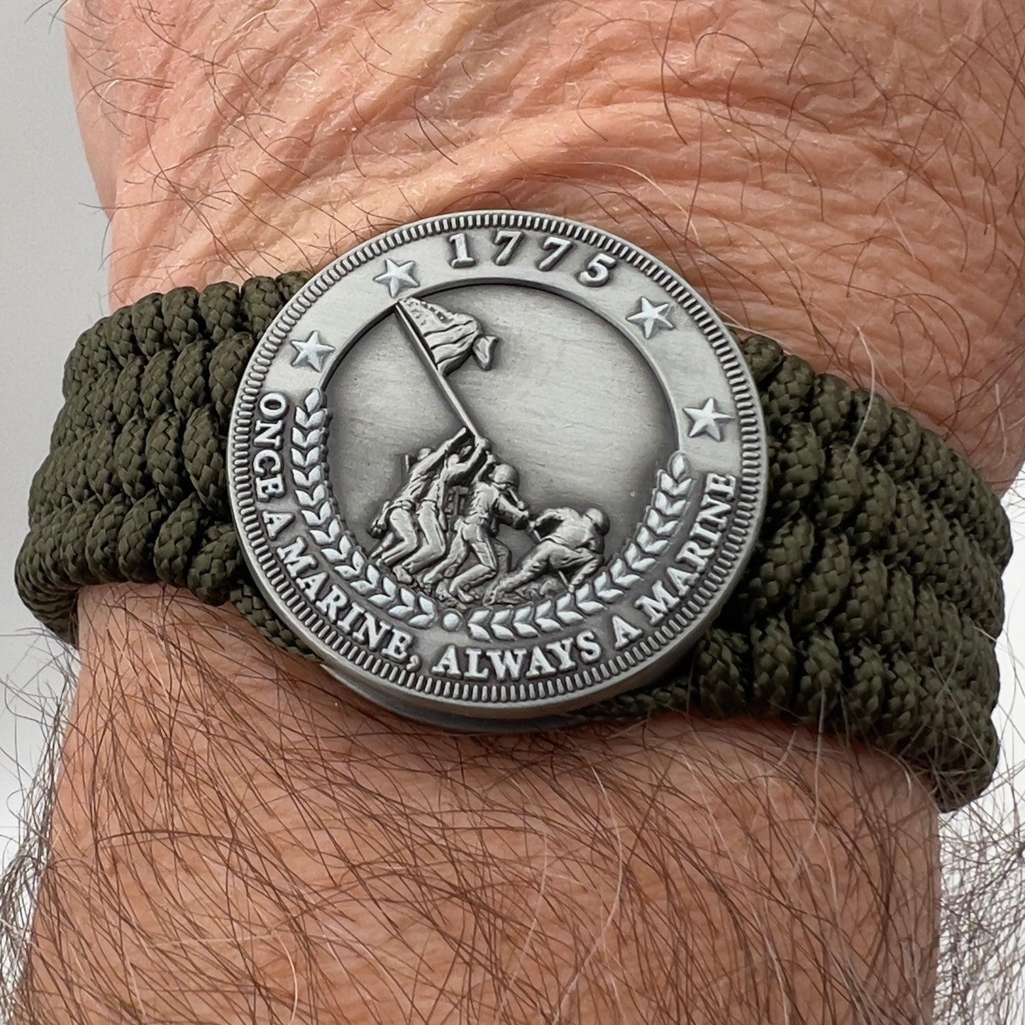 Thin, wide, flexible and comfortable braided United States Marine Corps Iwo Jima bracelet featuring an antique silver plated Iwo Jima flag raising medallion, a silver Cobra style tactical buckle and woven with olive drab type-1 paracord.
