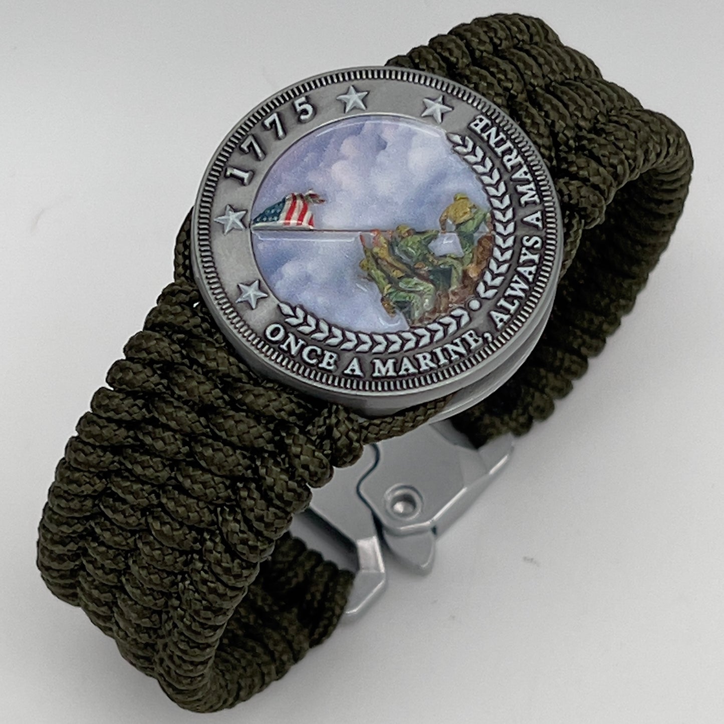 Thin, wide, flexible and comfortable braided United States Marine Corps Iwo Jima bracelet featuring an antique silver plated UV painted Iwo Jima flag raising medallion, a silver Cobra style tactical buckle and woven with olive drab Type-1 paracord.
