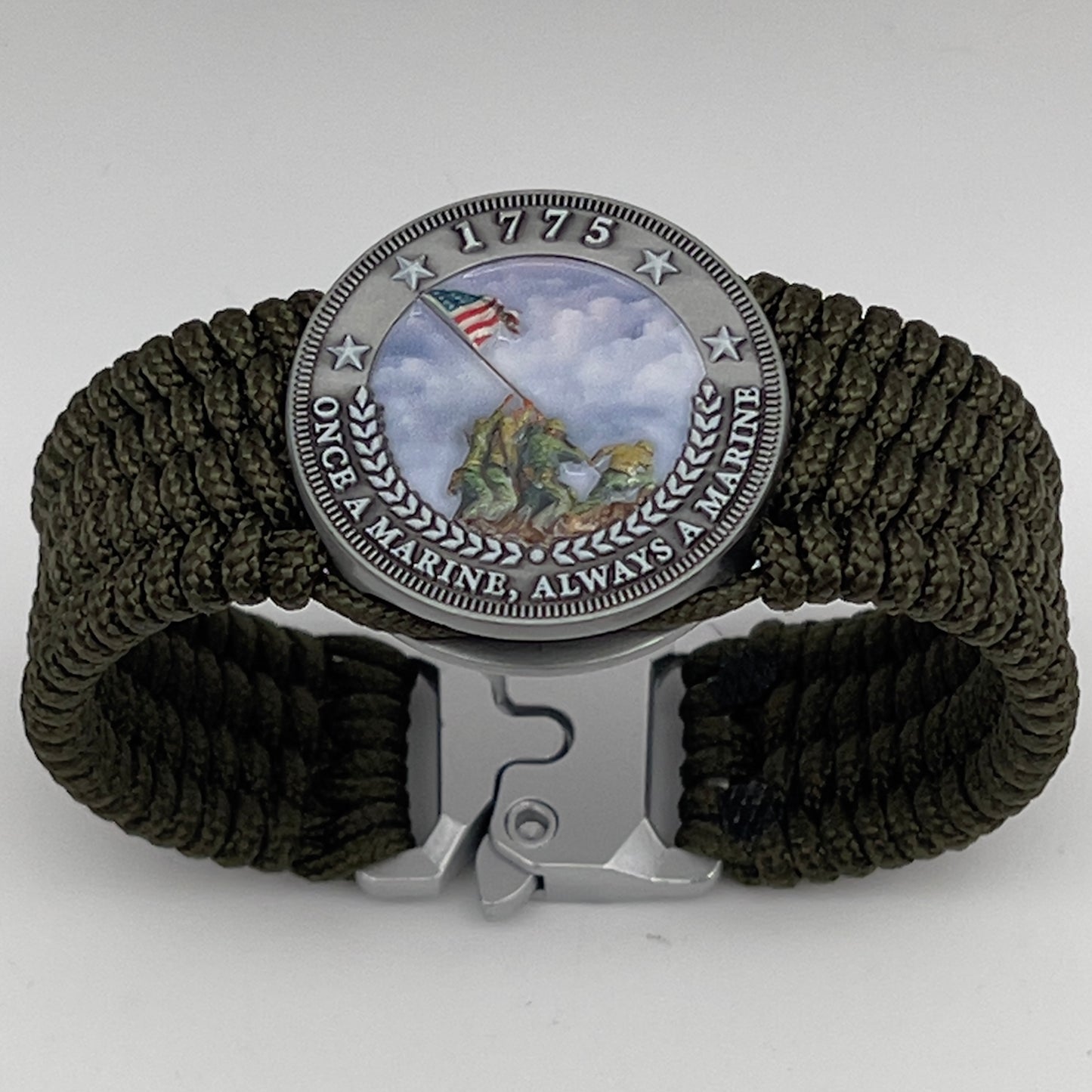 Thin, wide, flexible and comfortable braided United States Marine Corps Iwo Jima bracelet featuring an antique silver plated UV painted Iwo Jima flag raising medallion, a silver Cobra style tactical buckle and woven with olive drab Type-1 paracord.