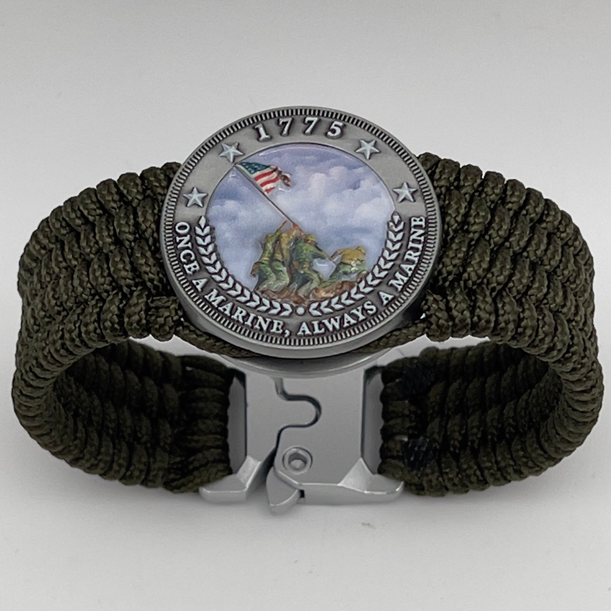 Thin, wide, flexible and comfortable braided United States Marine Corps Iwo Jima bracelet featuring an antique silver plated UV painted Iwo Jima flag raising medallion, a silver Cobra style tactical buckle and woven with olive drab Type-1 paracord.