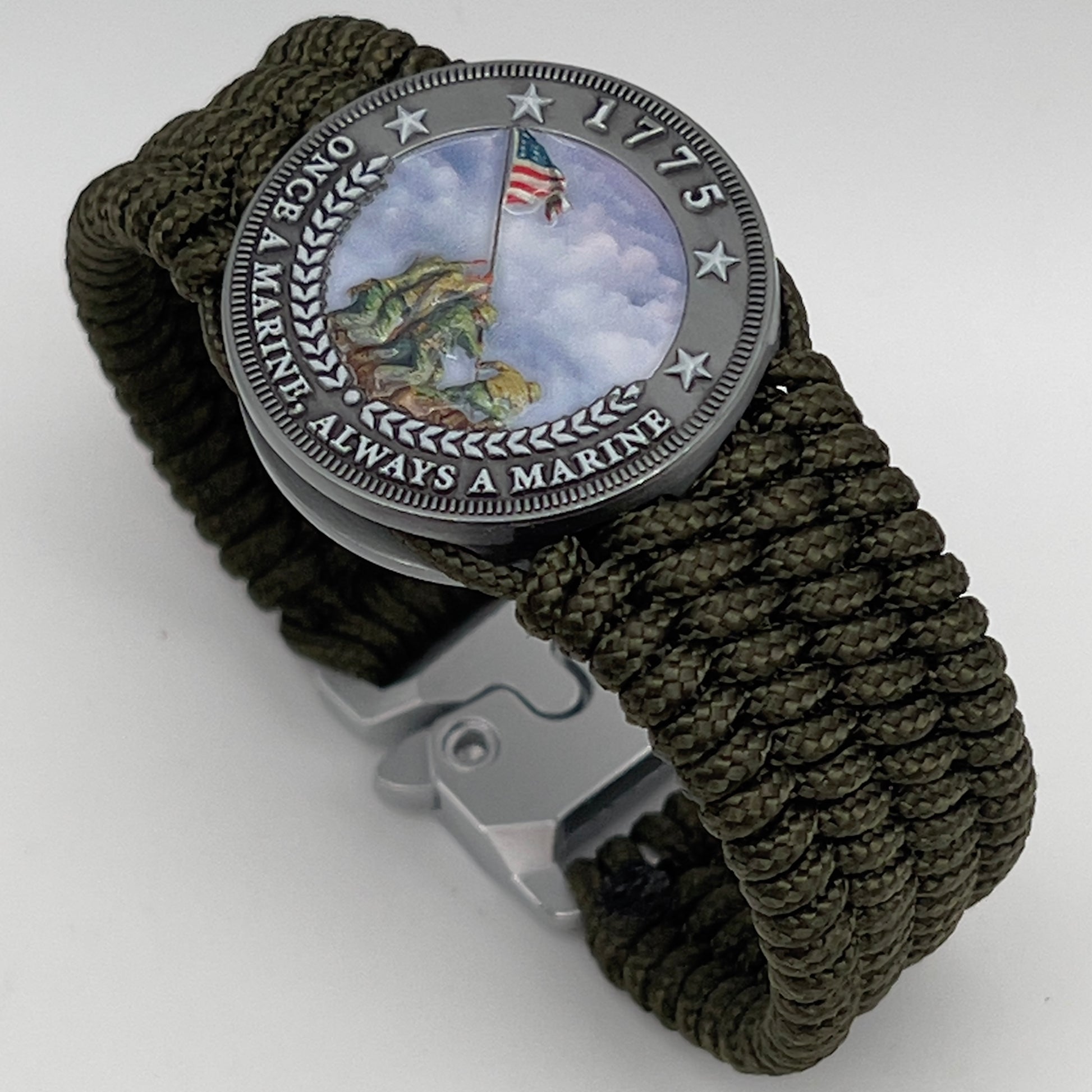 Thin, wide, flexible and comfortable braided United States Marine Corps Iwo Jima bracelet featuring an antique silver plated UV painted Iwo Jima flag raising medallion, a silver Cobra style tactical buckle and woven with olive drab Type-1 paracord.
