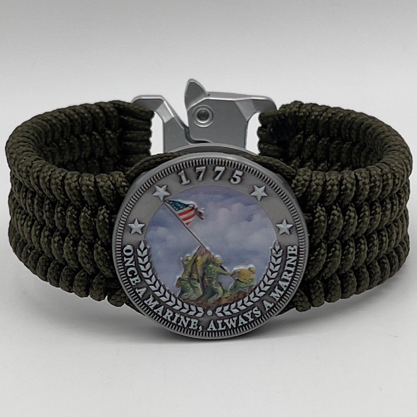 Thin, wide, flexible and comfortable braided United States Marine Corps Iwo Jima bracelet featuring an antique silver plated UV painted Iwo Jima flag raising medallion, a silver Cobra style tactical buckle and woven with olive drab Type-1 paracord.