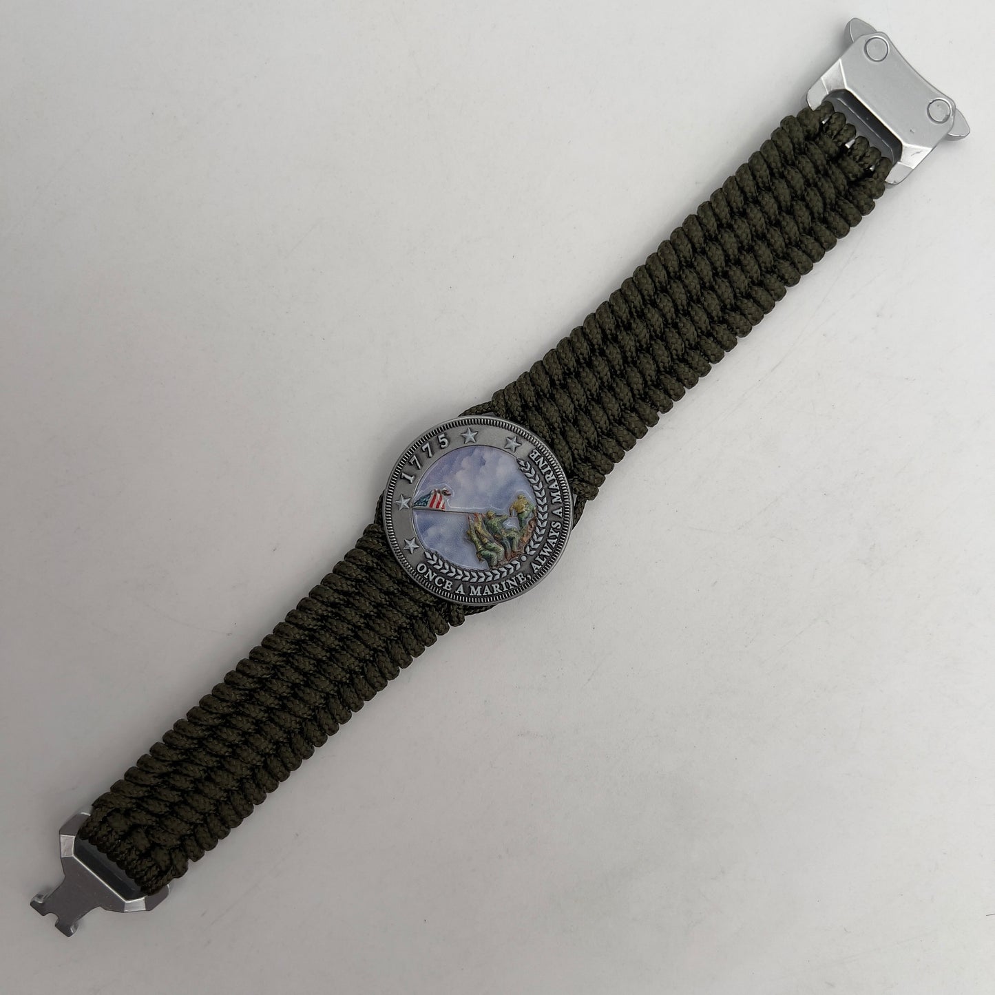 Thin, wide, flexible and comfortable braided United States Marine Corps Iwo Jima bracelet featuring an antique silver plated UV painted Iwo Jima flag raising medallion, a silver Cobra style tactical buckle and woven with olive drab Type-1 paracord.