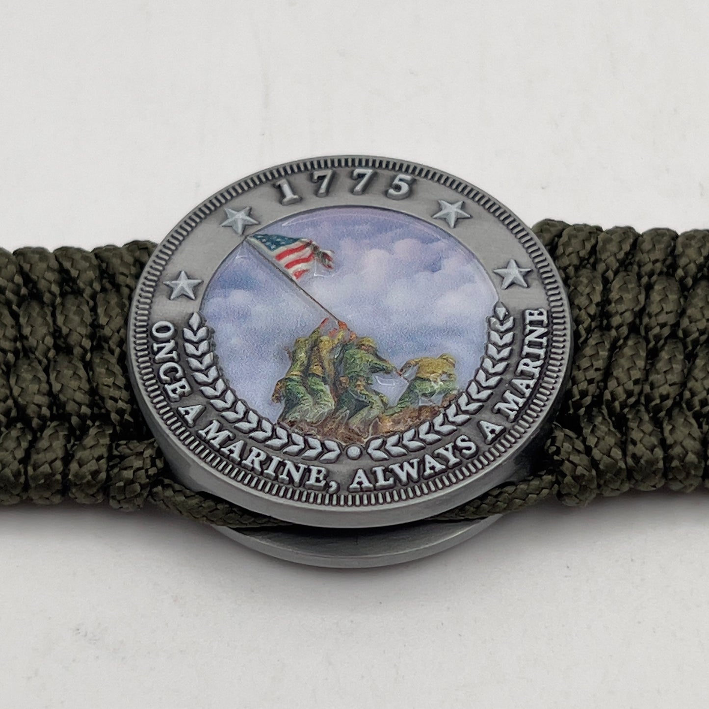 Thin, wide, flexible and comfortable braided United States Marine Corps Iwo Jima bracelet featuring an antique silver plated UV painted Iwo Jima flag raising medallion, a silver Cobra style tactical buckle and woven with olive drab Type-1 paracord.