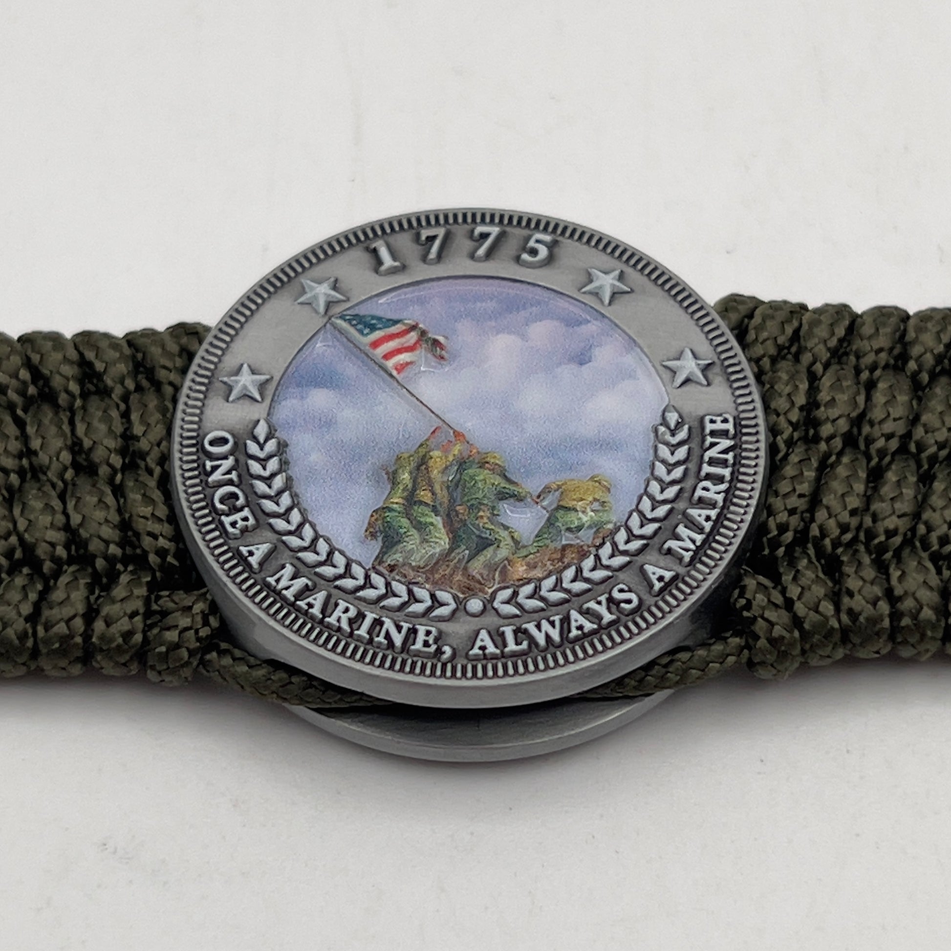 Thin, wide, flexible and comfortable braided United States Marine Corps Iwo Jima bracelet featuring an antique silver plated UV painted Iwo Jima flag raising medallion, a silver Cobra style tactical buckle and woven with olive drab Type-1 paracord.