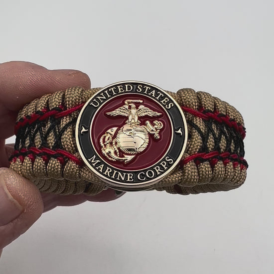 Thick, wide, rigid and comfortable braided United States Marine Corps bracelet featuring a 24K gold plated USMC Eagle Globe and Anchor medallion, a gold Cobra style tactical buckle and woven with gold 550 paracord and Imperial Red micro and black nano cord.