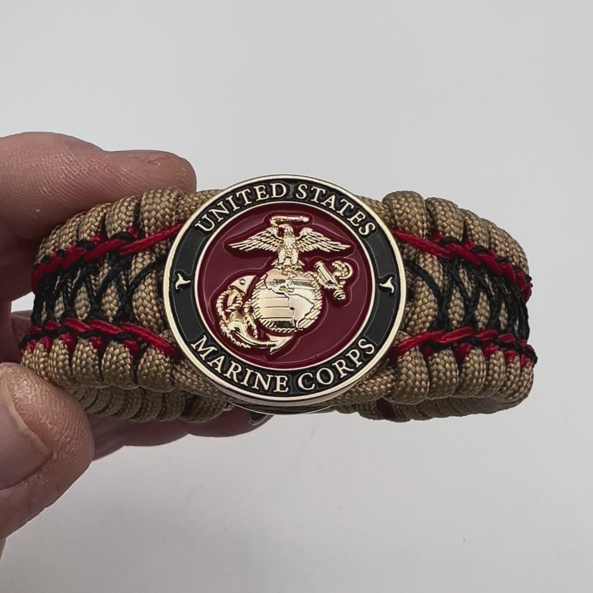 Thick, wide, rigid and comfortable braided United States Marine Corps bracelet featuring a 24K gold plated USMC Eagle Globe and Anchor medallion, a gold Cobra style tactical buckle and woven with gold 550 paracord and Imperial Red micro and black nano cord.