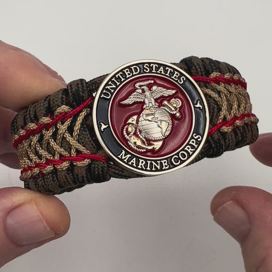 Thick, rigid and comfortable braided United States Marine Corps bracelet featuring a 24K gold and silver plated USMC officer Eagle Globe and Anchor medallion, a gold Cobra style tactical buckle and woven with Woodland Camo 550 paracord and Imperial Red and gold micro cord.