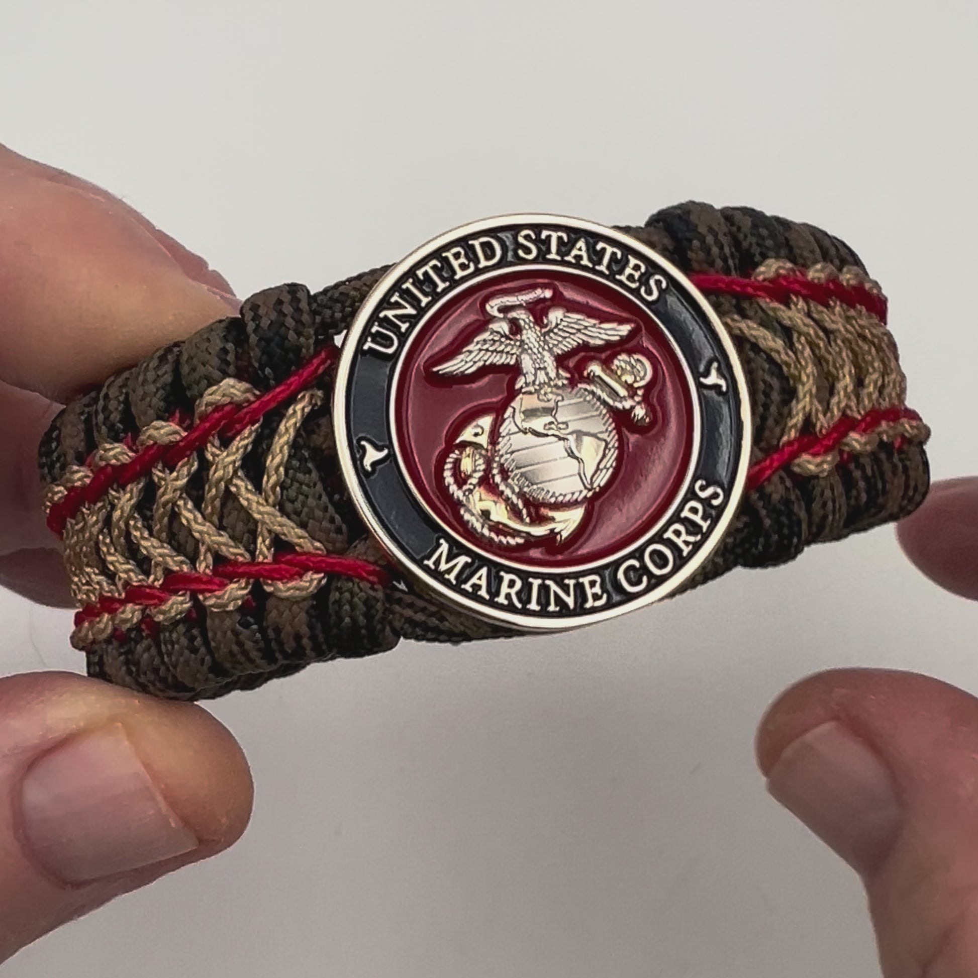 Thick, rigid and comfortable braided United States Marine Corps bracelet featuring a 24K gold and silver plated USMC officer Eagle Globe and Anchor medallion, a gold Cobra style tactical buckle and woven with Woodland Camo 550 paracord and Imperial Red and gold micro cord.