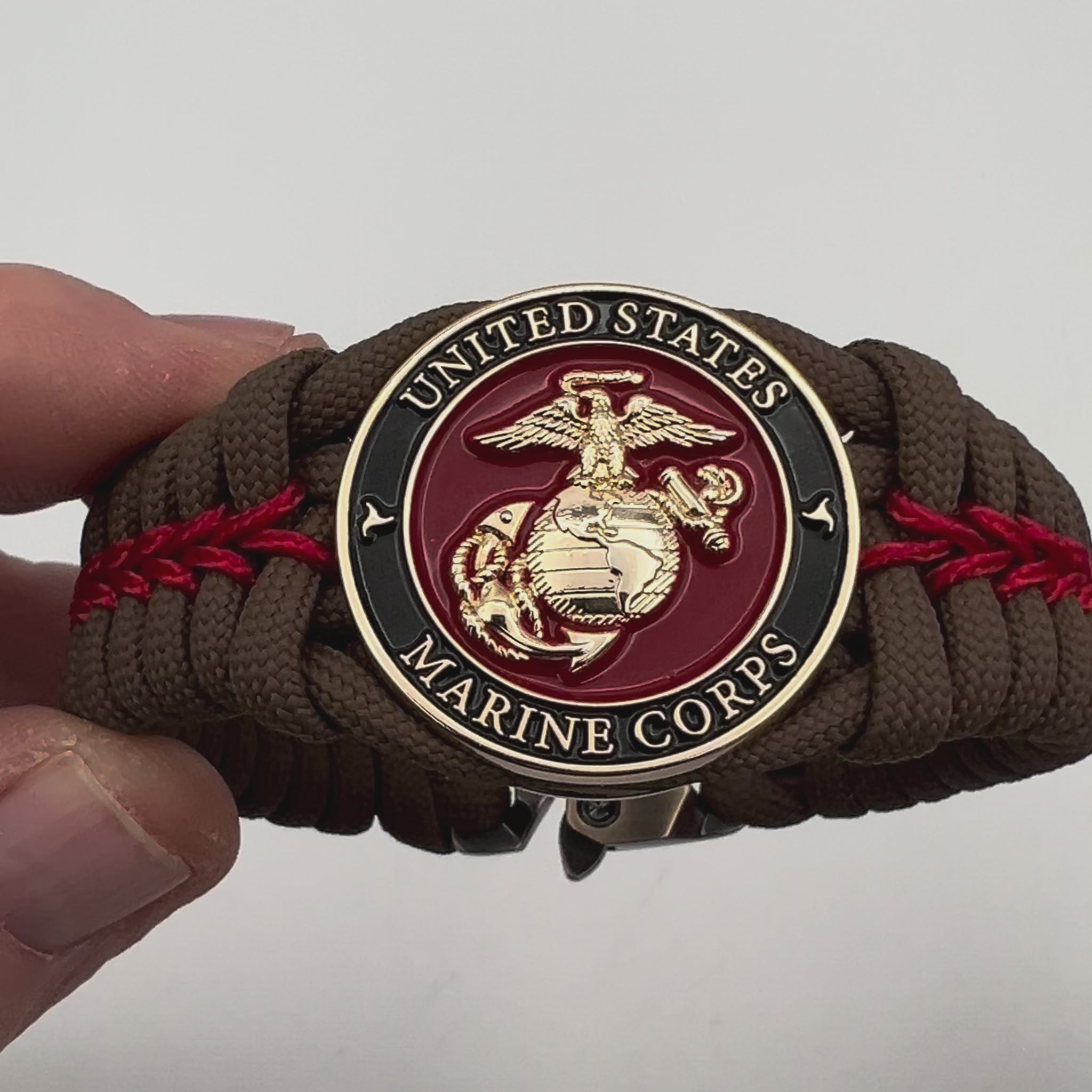 Thick, rigid and comfortable braided United States Marine Corps bracelet featuring a 24K gold plated USMC Eagle Globe and Anchor medallion, a gold Cobra style tactical buckle and woven with Coyote Brown 550 paracord and Imperial Red micro cord.