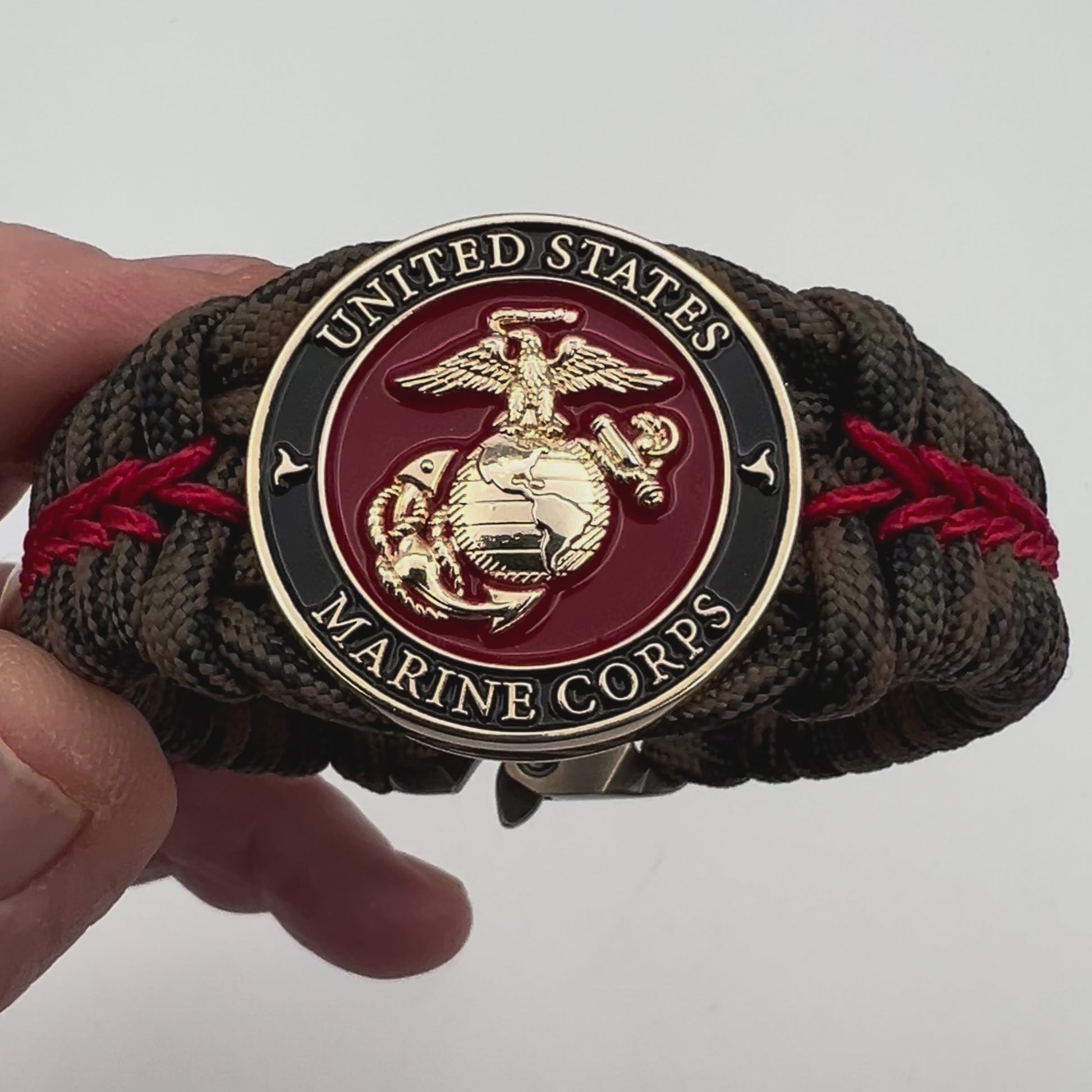 Thick, rigid and comfortable braided United States Marine Corps bracelet featuring a 24K gold plated USMC Eagle Globe and Anchor medallion, a gold Cobra style tactical buckle and woven with Woodland Camo 550 paracord and Imperial Red micro cord.